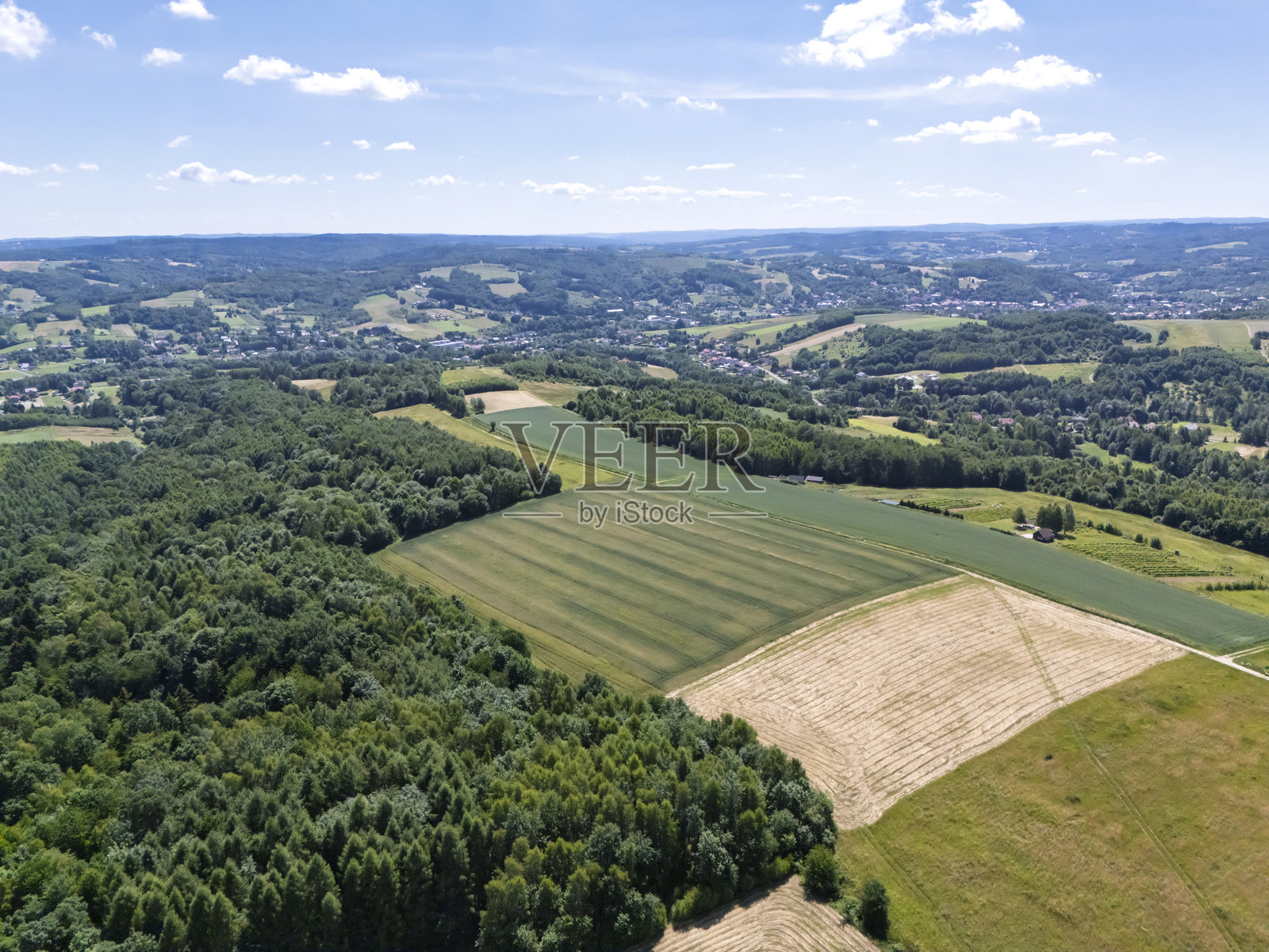 清澈蓝天下郁郁葱葱的田野和森林的鸟瞰图，展示了乡村的自然美。照片摄影图片
