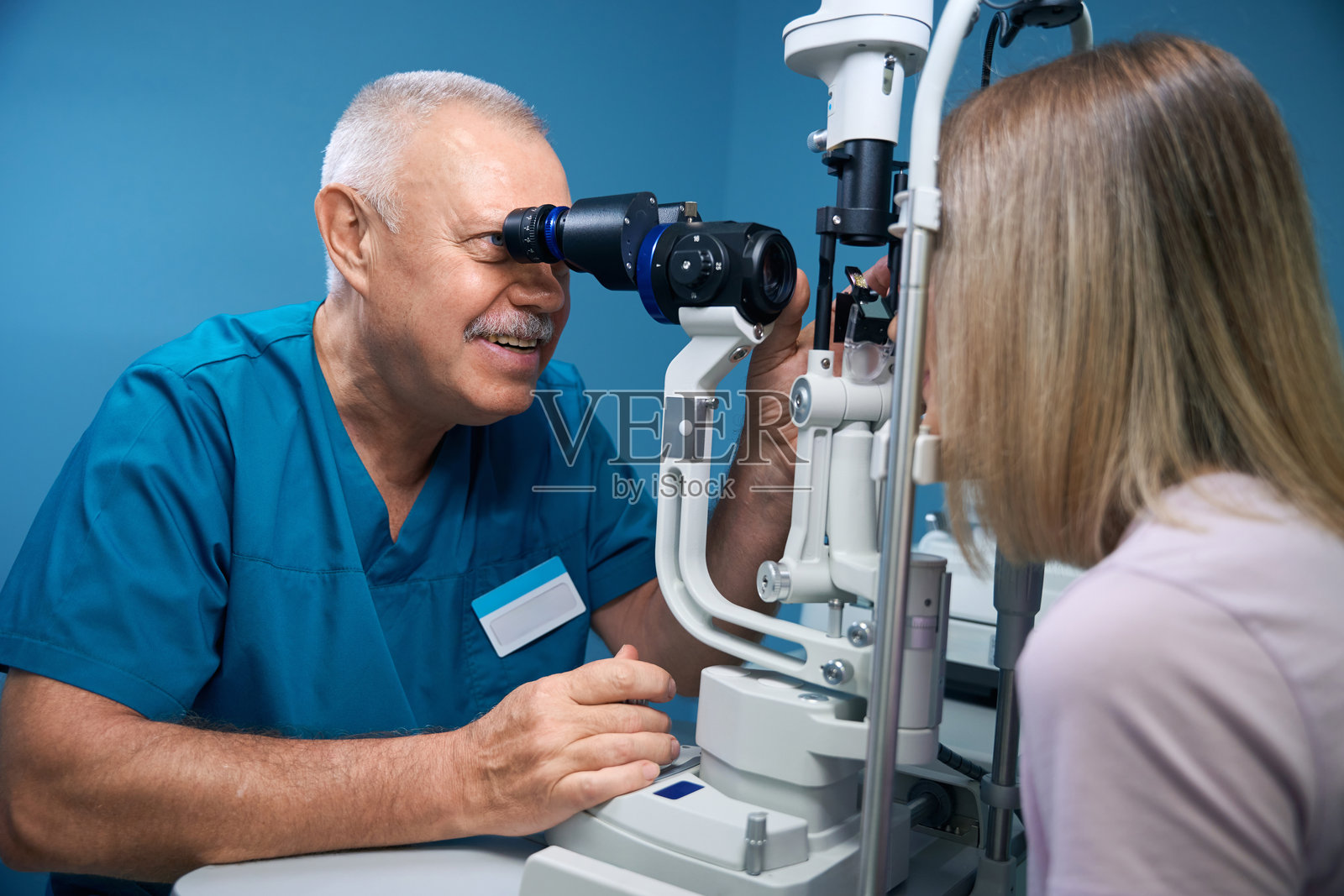 微笑的眼科医生正在使用特殊的眼科设备为女性测试视力照片摄影图片