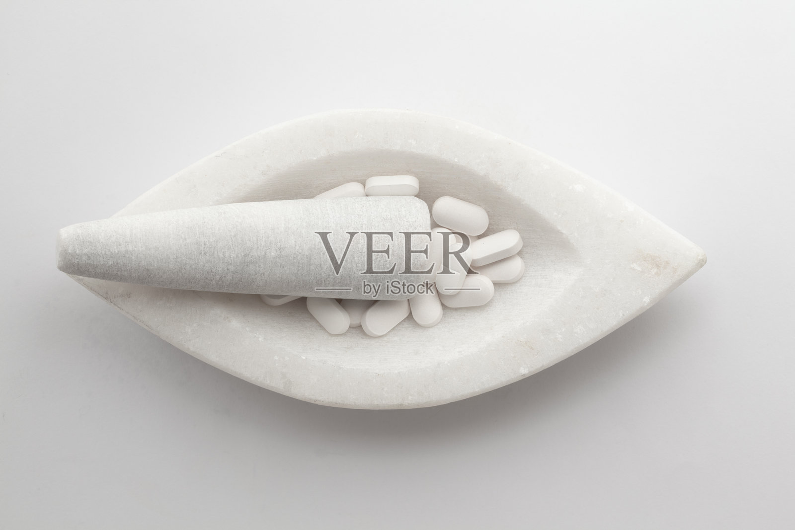 白色药丸和片剂的特写，放在白色大理石研钵和研杵上。照片摄影图片