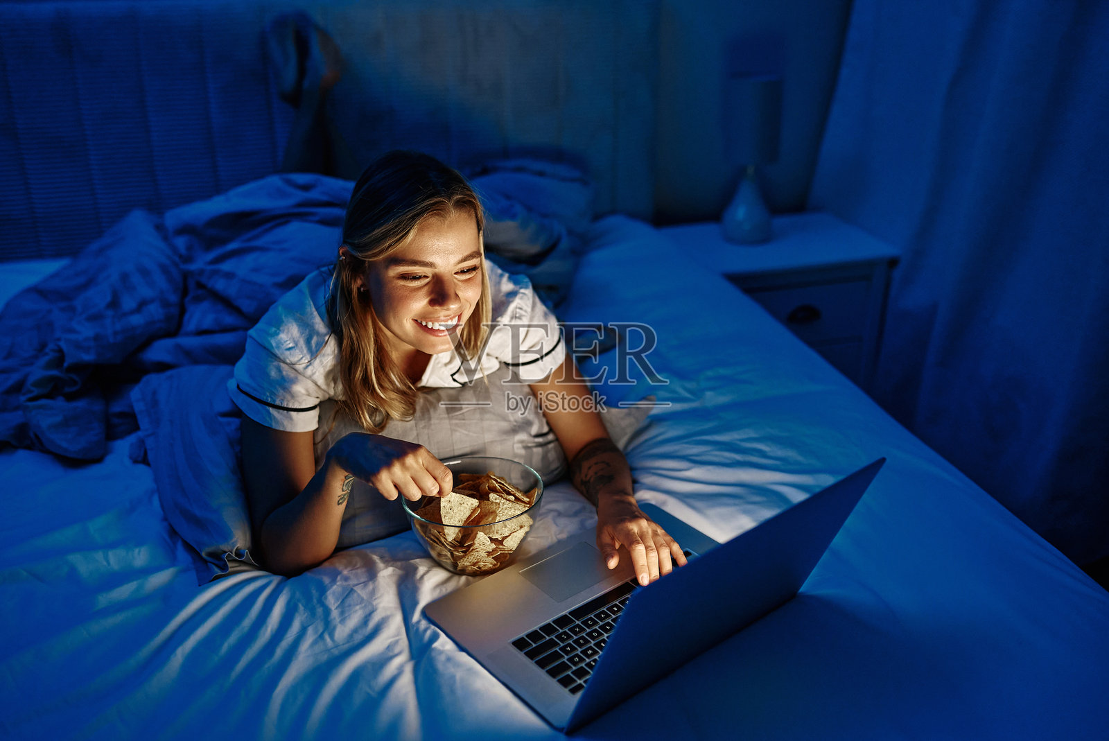 在床上舒适地享受美味的深夜电影体验，同时品尝冰淇淋照片摄影图片