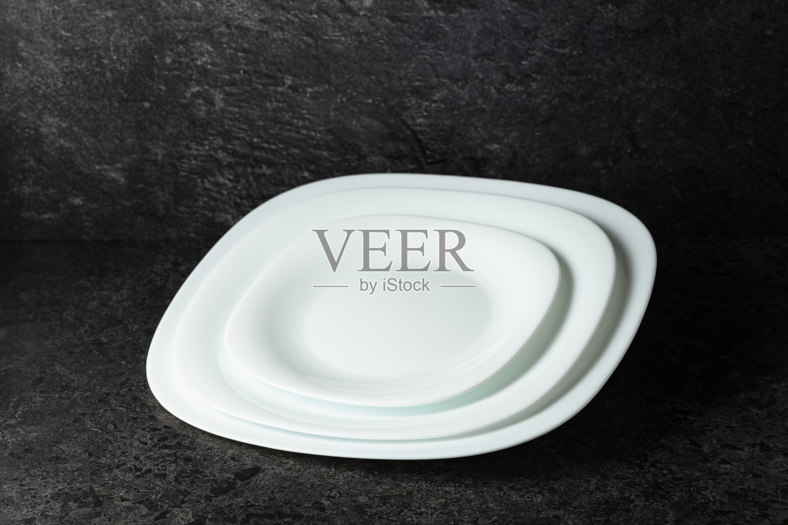 黑色石材背景上的空白白盘，留有空白空间。照片摄影图片