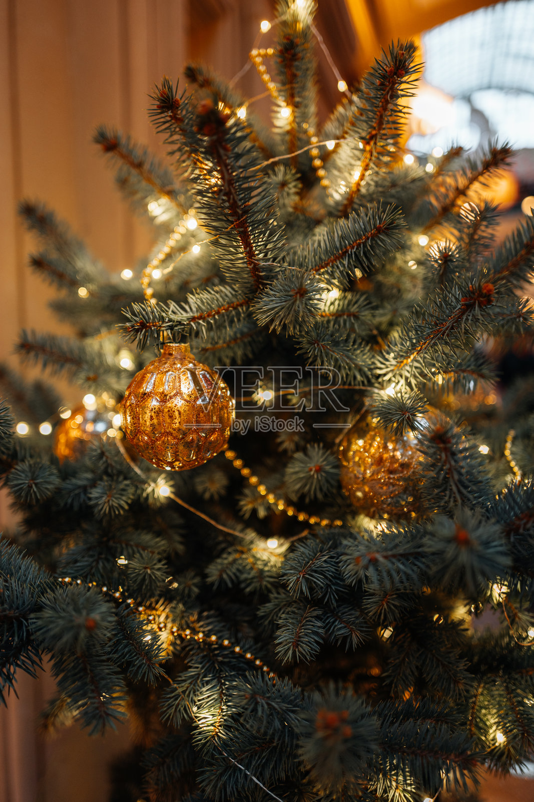 金色圣诞球和灯饰花环挂在圣诞树上，节日背景照片摄影图片
