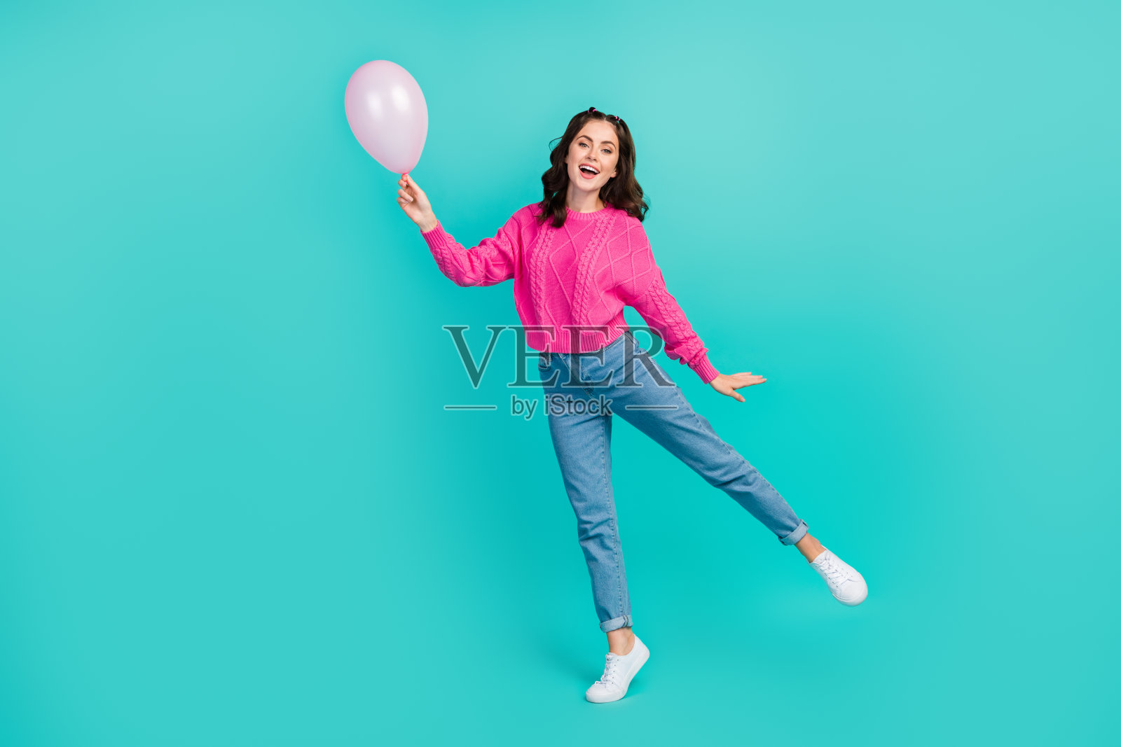 全身照，年轻迷人漂亮的女性手持气球，玩耍般快乐地庆祝生日，背景为水绿色。照片摄影图片