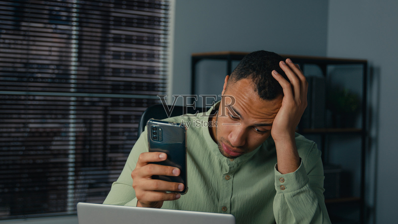 沮丧、压力大、心烦意乱、担忧的非裔美国男商人，男性企业家，员工在办公室查看手机上的坏消息，面临商业问题、危机、软件错误和损失。照片摄影图片