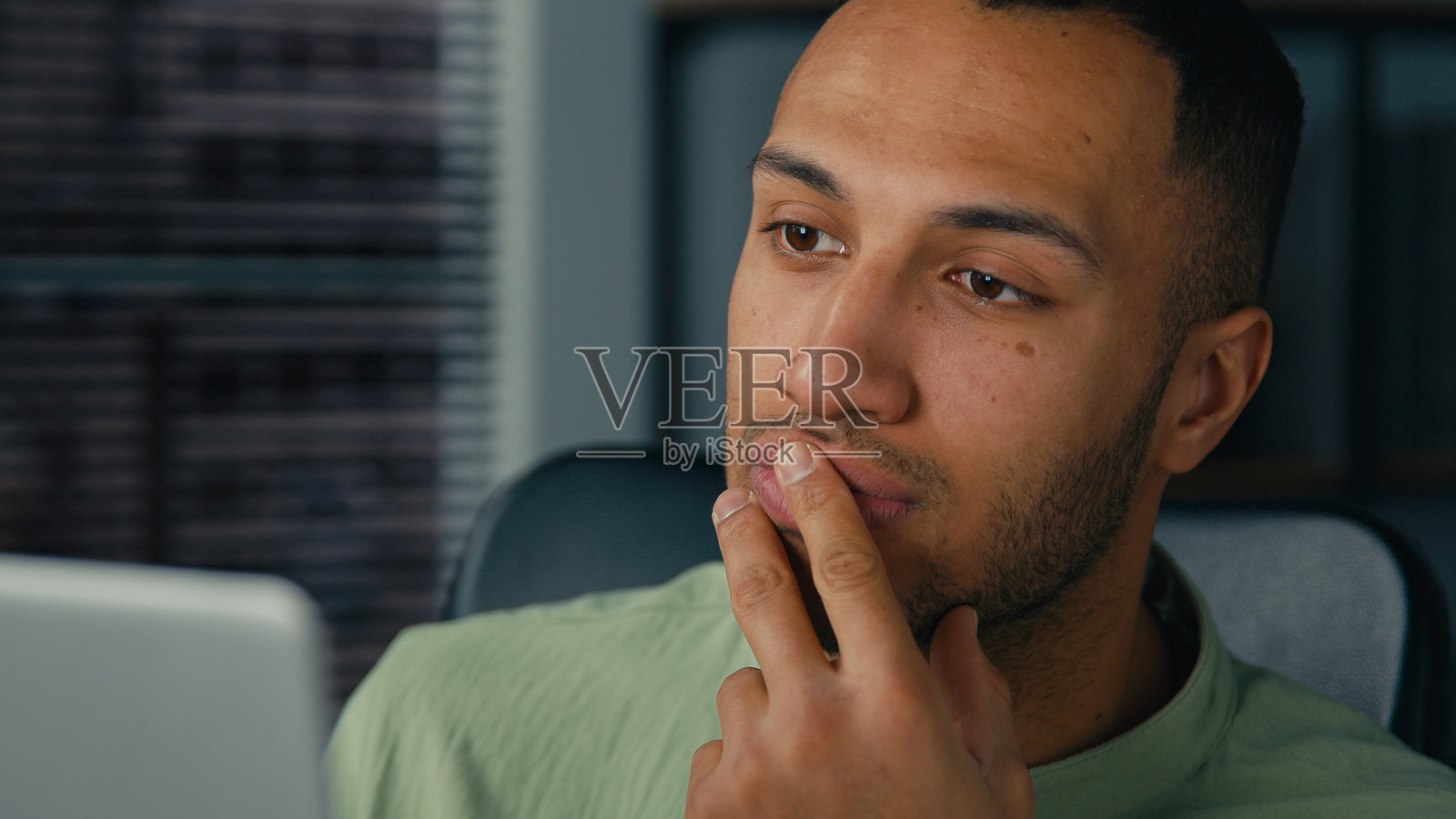 非裔美国男性经理正在查看笔记本电脑屏幕，撰写财务报告，分析来自互联网的数据；年轻的少数族裔商人在办公室工作，做笔记，处理文书工作，准备演示文稿。照片摄影图片