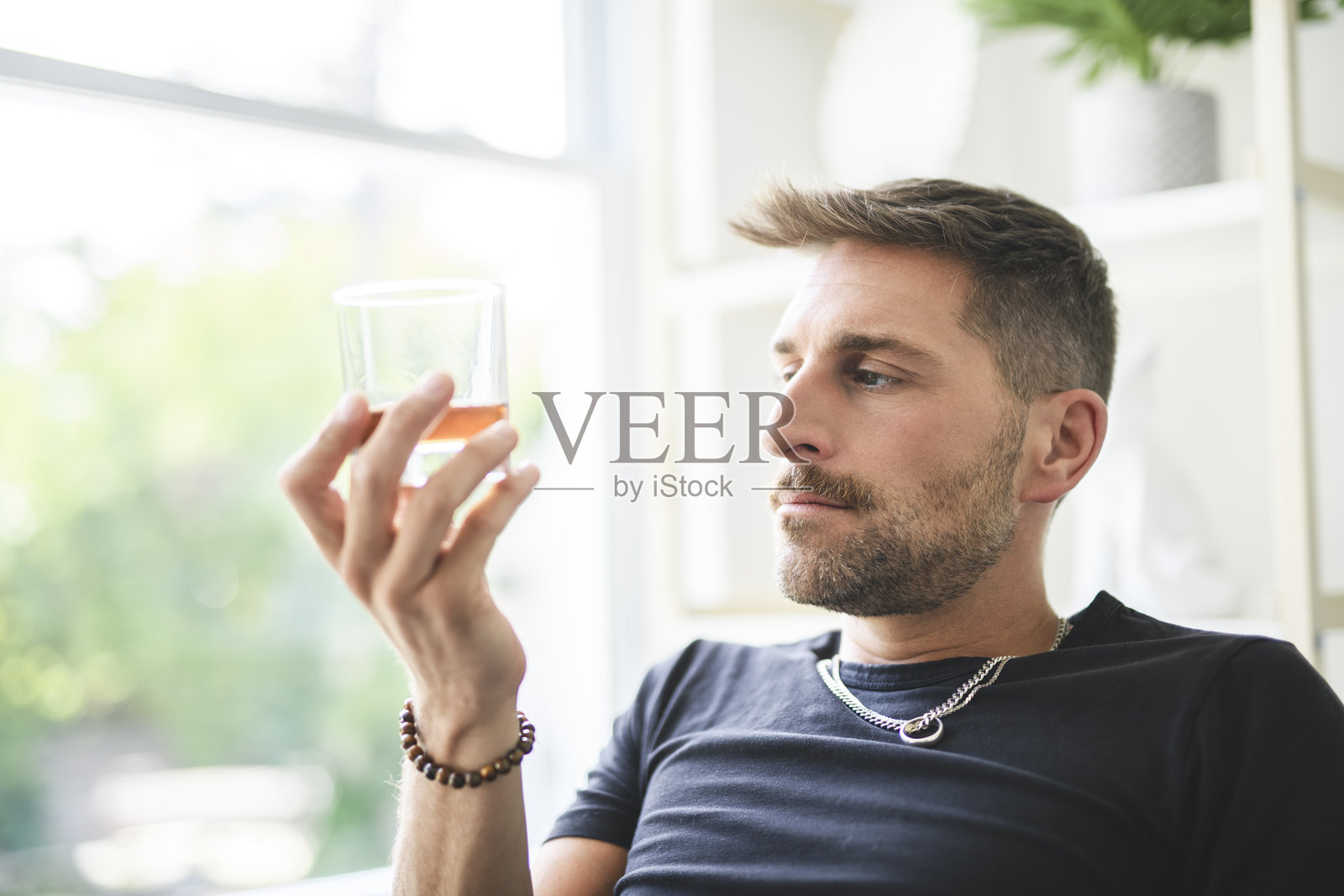 孤独沮丧的男性在家沙发上喝酒。酒精成瘾的治疗，遭受酗酒问题的困扰。照片摄影图片