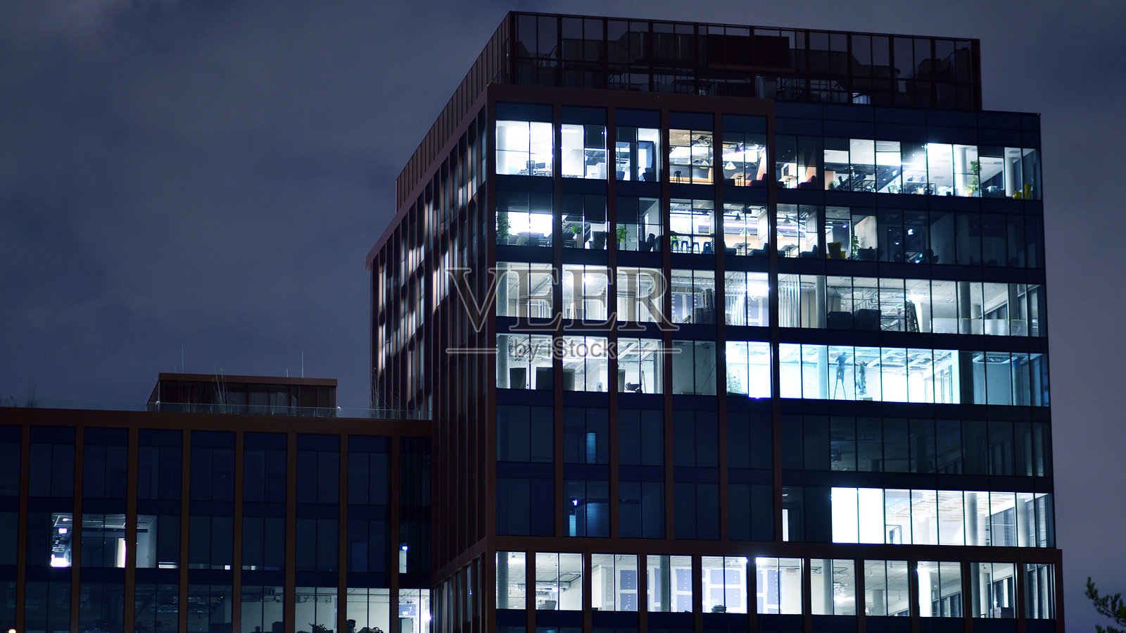 傍晚时分的办公大楼，工作空间灯光明亮。照片摄影图片