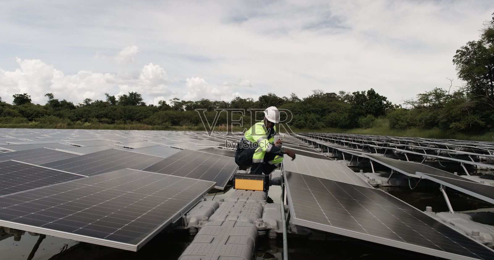 光伏工程师在浮动光伏项目上工作。检查和修理漂浮在水面上的太阳能电池板设备。照片摄影图片