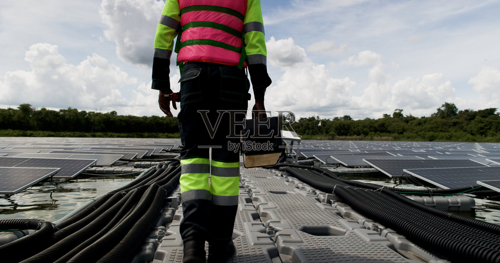 光伏工程师在浮动光伏项目上工作。检查和修理漂浮在水面上的太阳能电池板设备。照片摄影图片