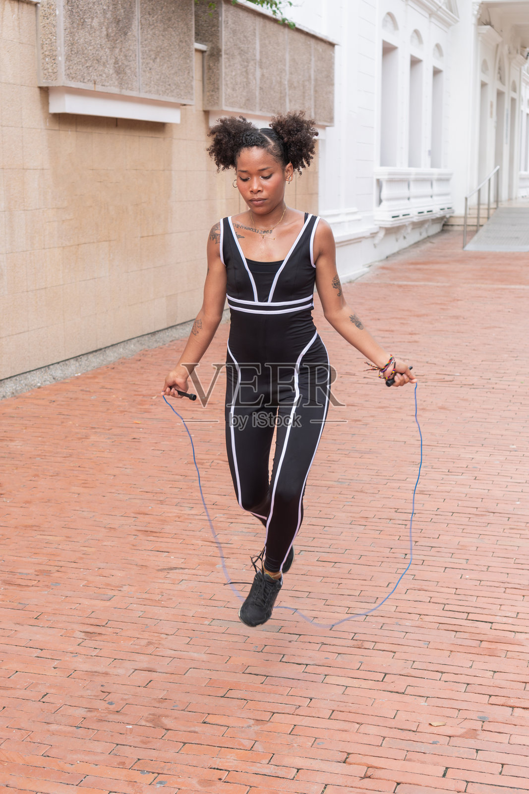 穿着运动服的拉丁裔女性在户外跳绳照片摄影图片