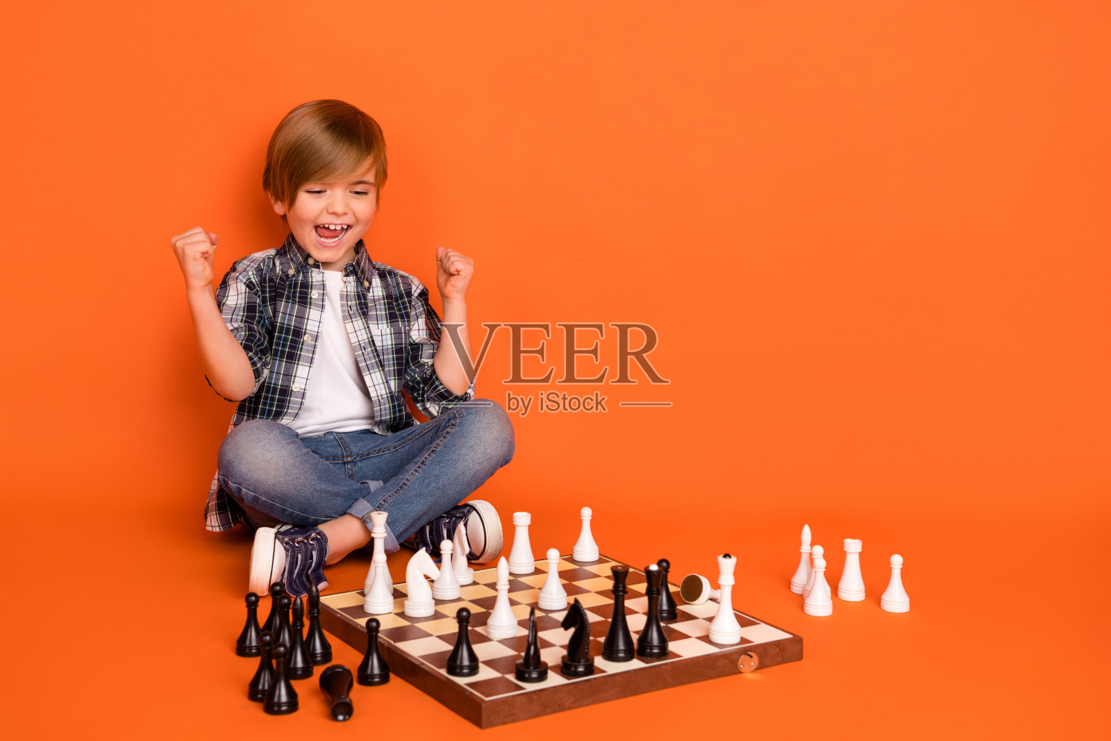 年轻男孩兴奋地庆祝胜利，双拳挥舞，太棒了！背景为橙色。照片摄影图片