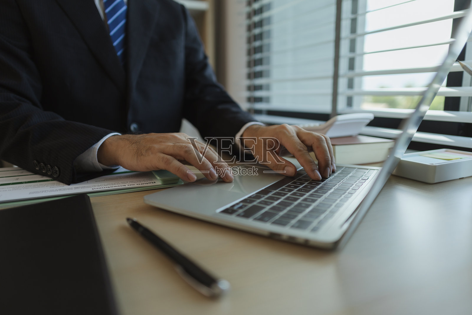 一位商人在办公室里坐着，手中拿着文件以分析数据。一位公司的高管穿着西装，显得庄重，以展示他作为公司所有者的身份。照片摄影图片