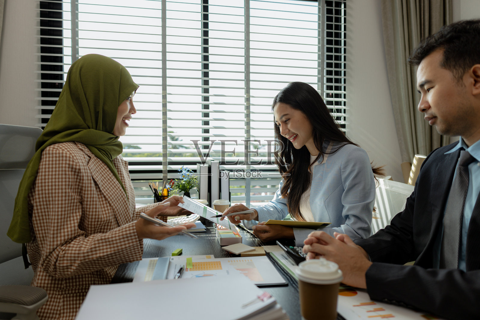 一群商人在办公室讨论。不同文化的商人们聚在一起，致力于开发符合宗教要求的产品。一位女商人戴着头巾。照片摄影图片
