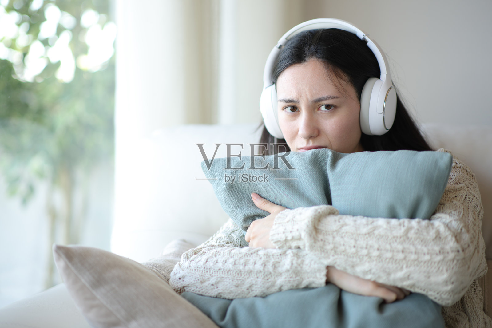 伤心的亚洲女性在听音频并注视着你照片摄影图片