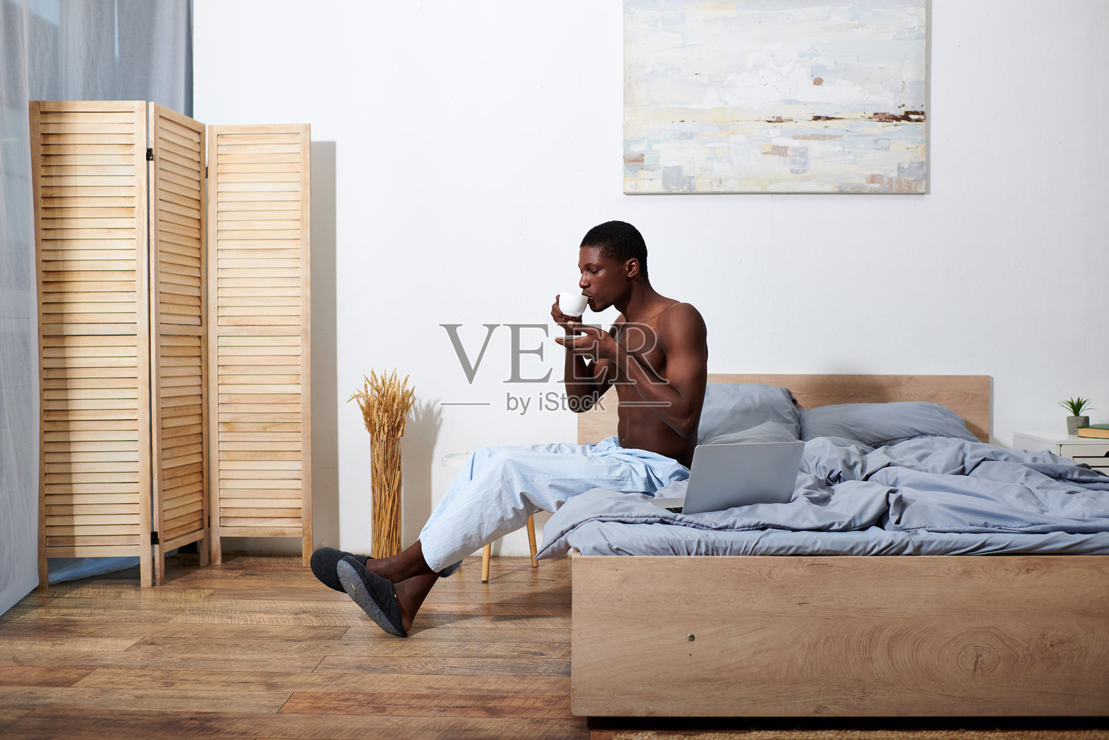 年轻帅气的男士在温馨的卧室环境中享受宁静的早晨和茶。照片摄影图片