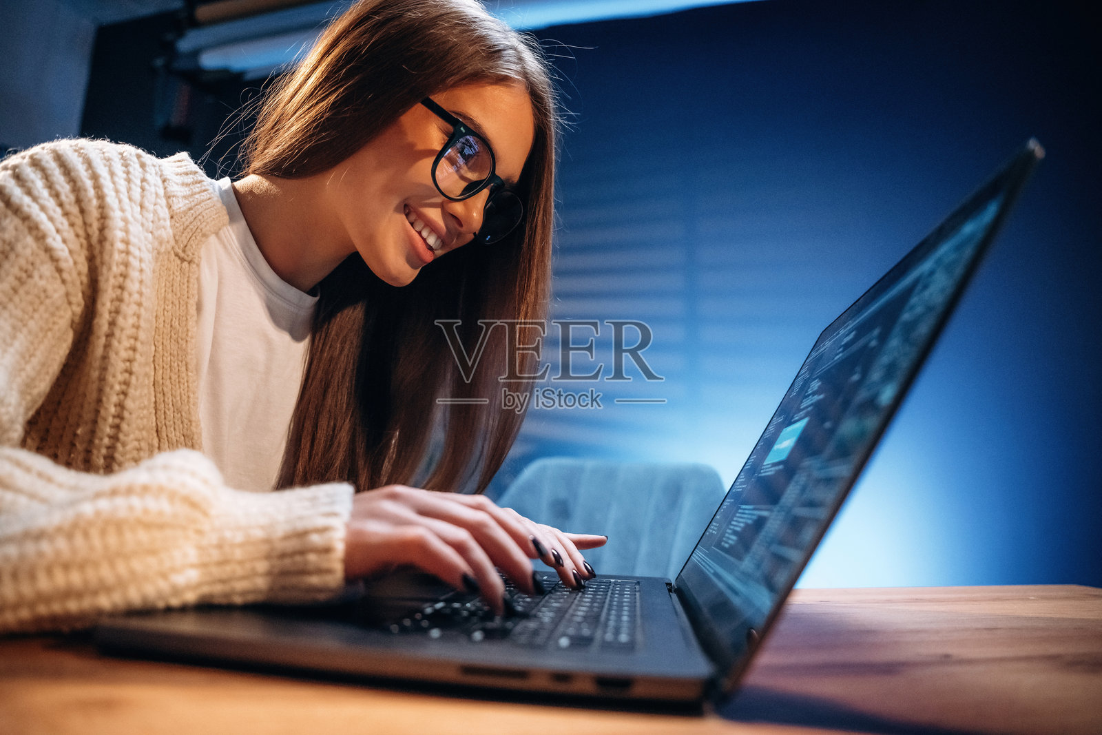 眼镜中的倒影。女性程序员，IT工作者坐在笔记本电脑旁。照片摄影图片