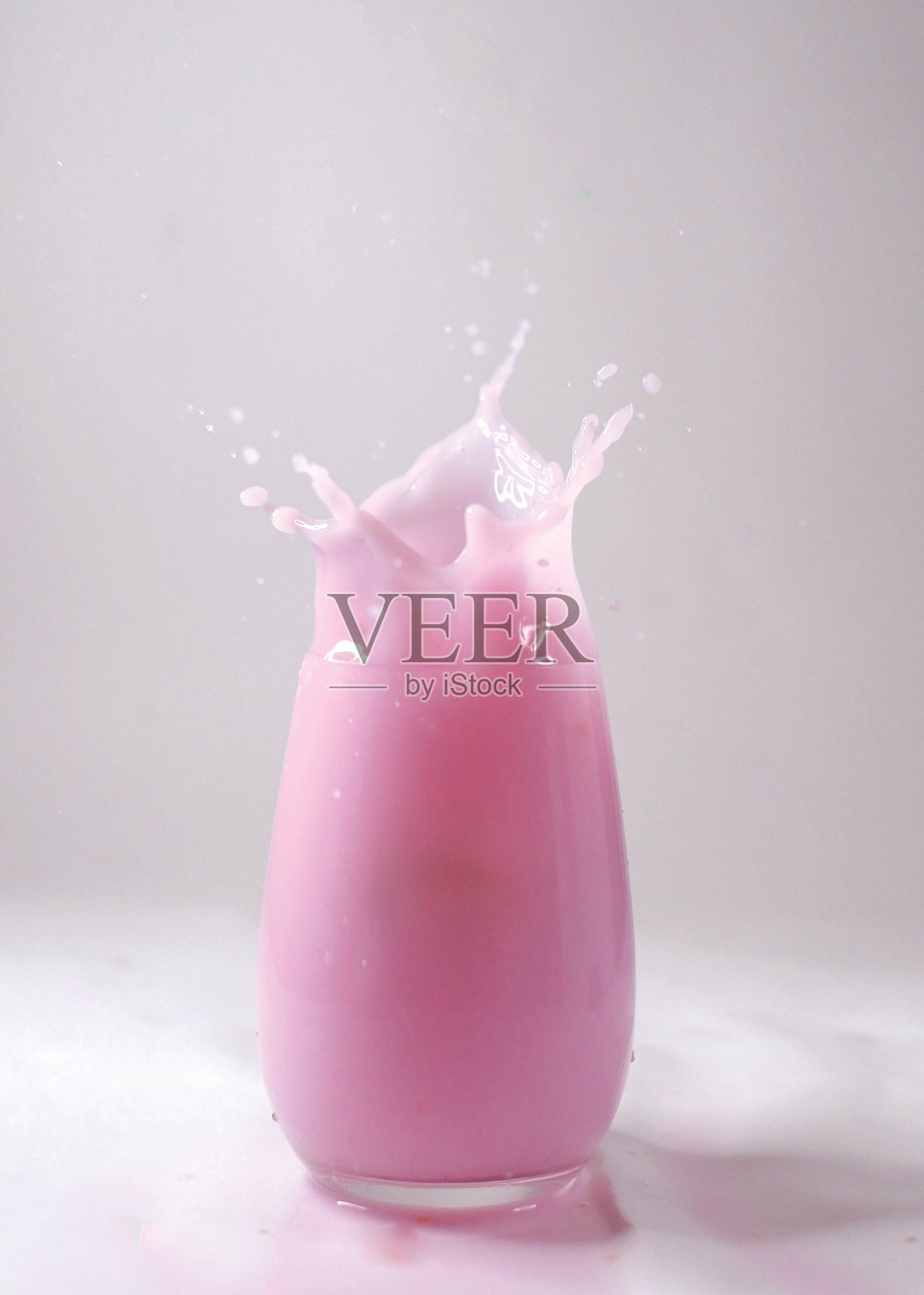 一杯草莓冰沙，伴有飞溅效果，背景为白色。照片摄影图片