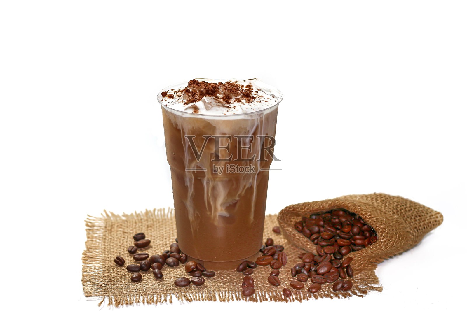 卡布奇诺冰咖啡在白色麻袋上盛放，配有泡沫牛奶和可可粉，突出孤立概念。照片摄影图片
