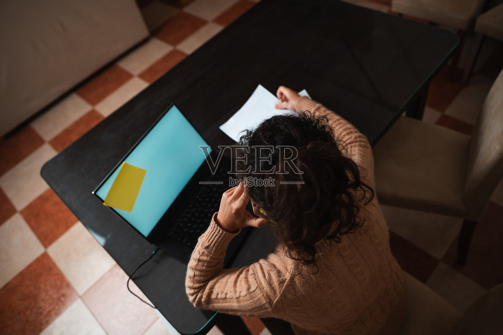 在家办公桌上，女性正在使用笔记本电脑处理文件照片摄影图片