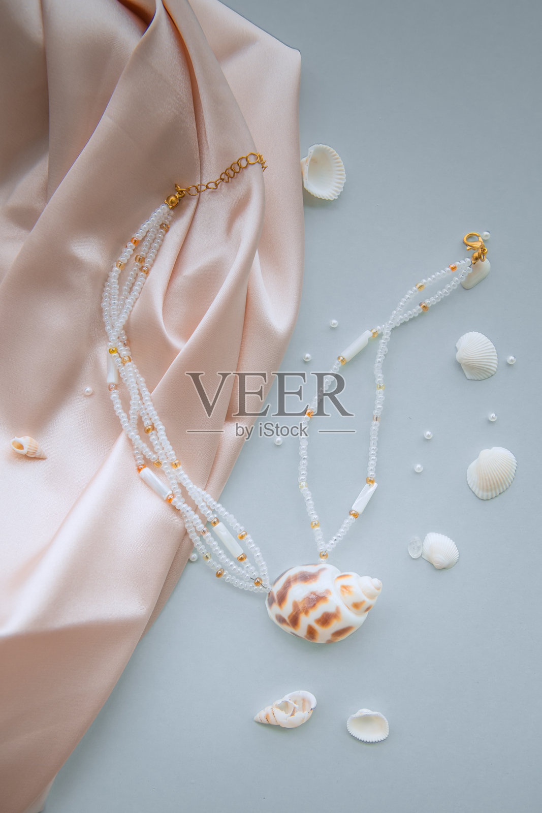 由海贝和白色珠子制成的吊坠项链，周围环绕着小海贝和珍珠照片摄影图片