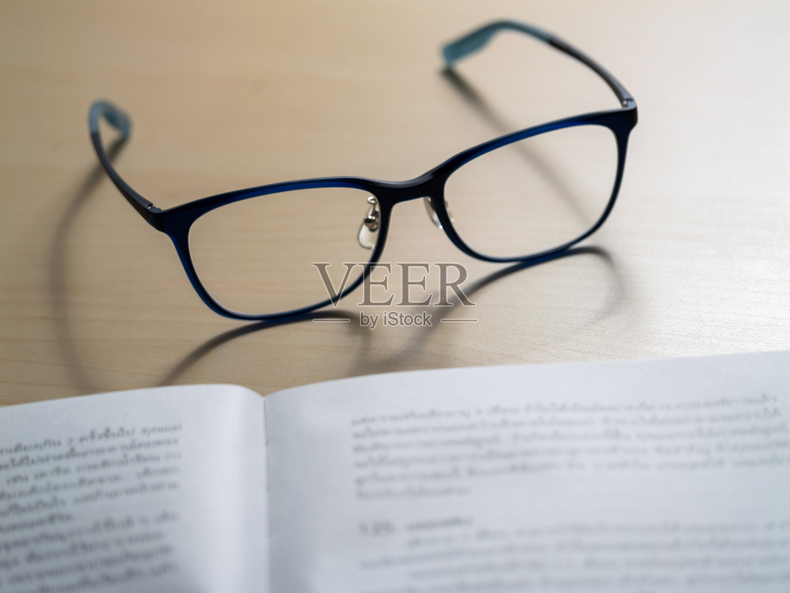 家办公桌上的书页上放着阅读眼镜，极简主义静物特写，专注于学习照片摄影图片