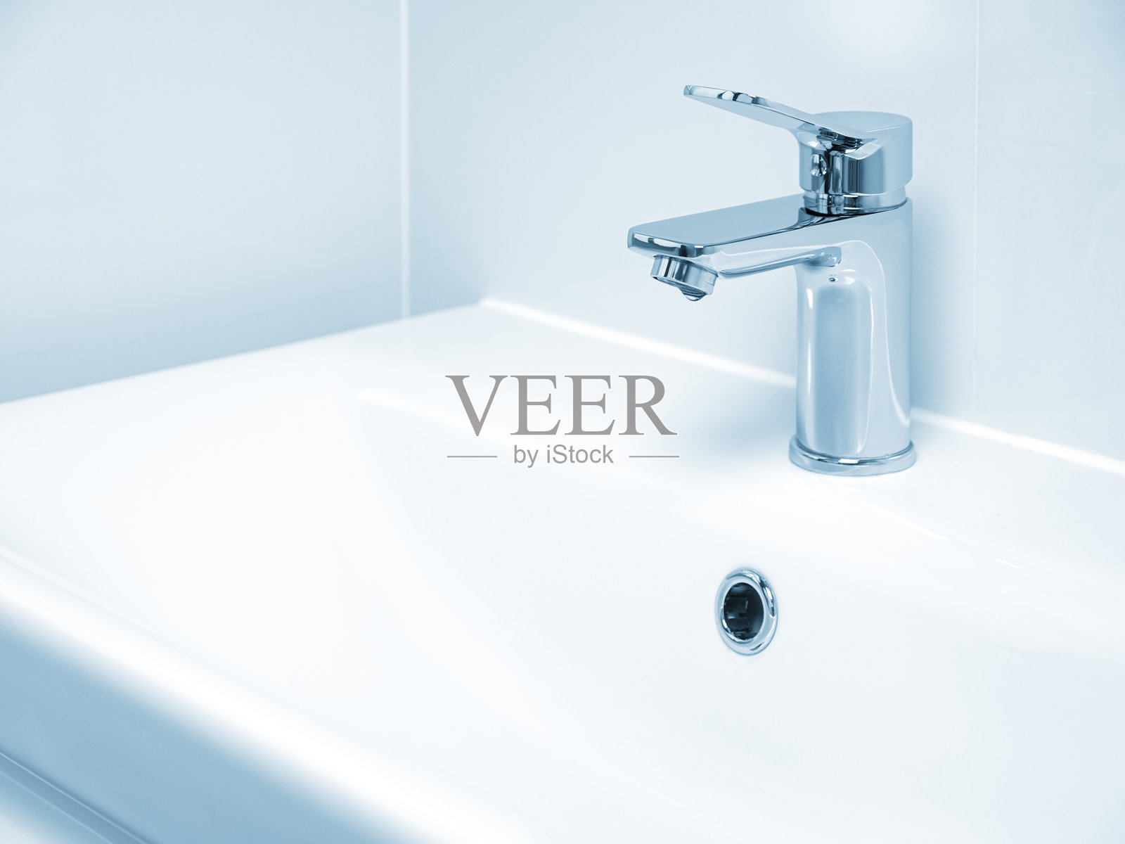 水龙头滴水特写。水的泄漏和浪费。蓝色调照片摄影图片