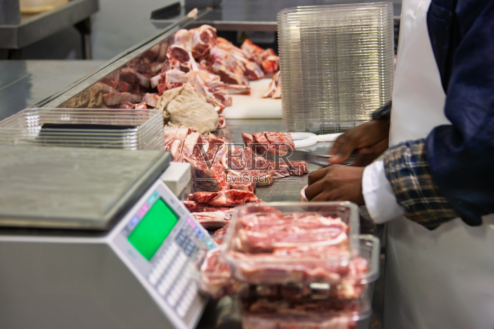 在工厂用塑料托盘包装肉类，牛排在不锈钢台面上的电子秤上称重。照片摄影图片