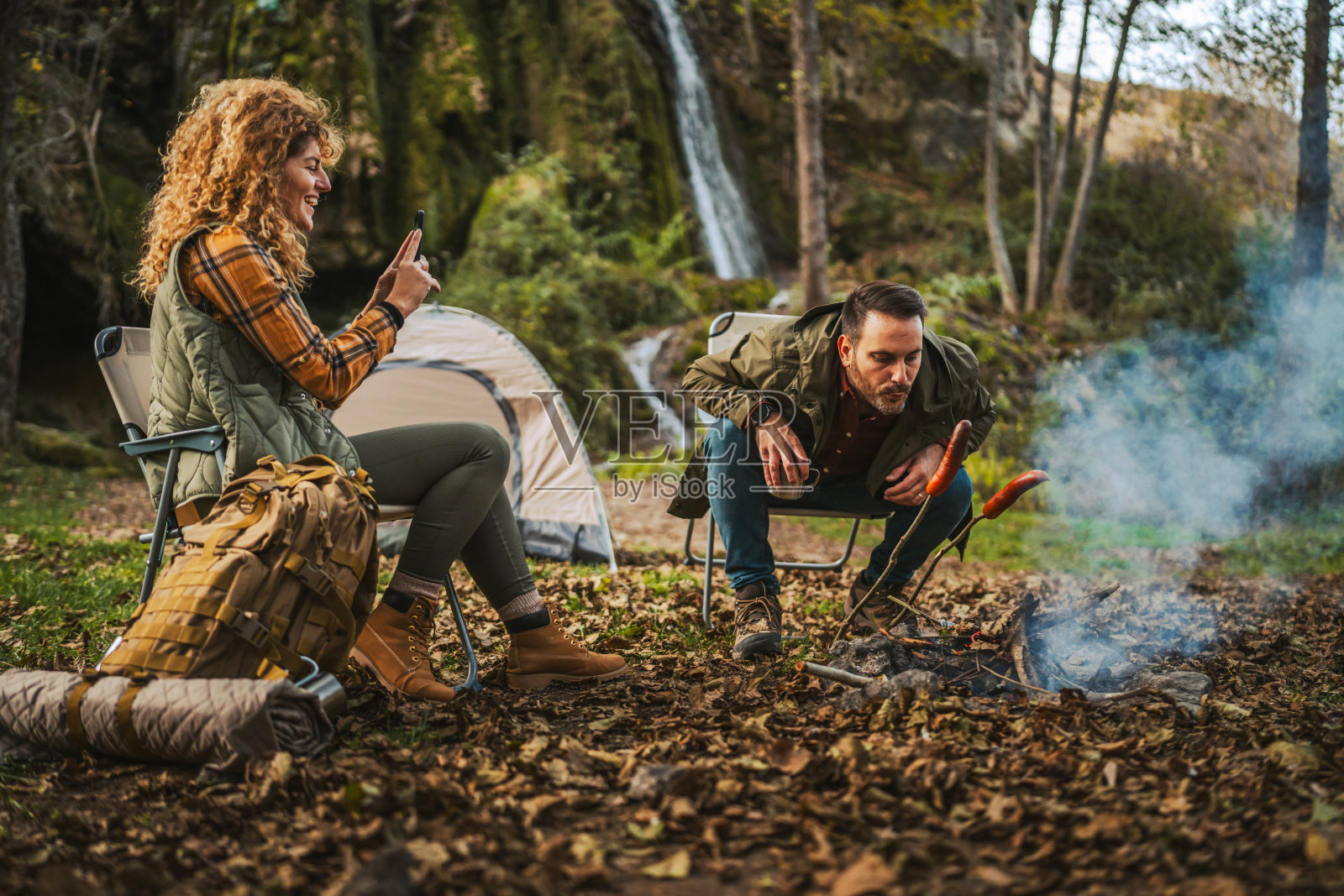 成年男性徒步旅行者跪下用木材生火，为露营做准备照片摄影图片