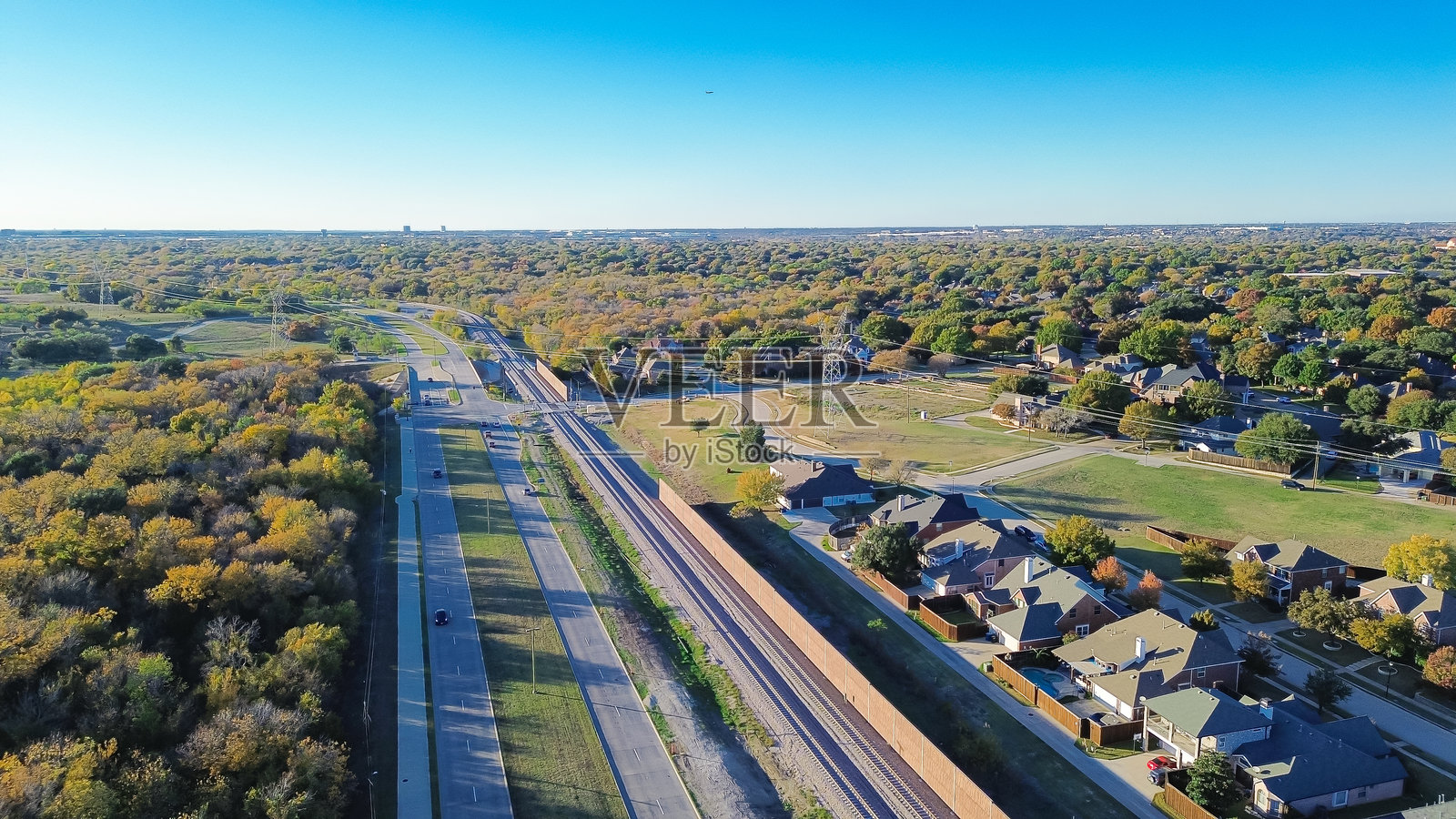 达拉斯-沃斯堡郊区郁郁葱葱的绿色区域，五彩斑斓的秋叶，豪华的郊区上方有电线杆，预制混凝土墙作为噪音屏障，轻轨贝尔特线公路的声音缓解。照片摄影图片