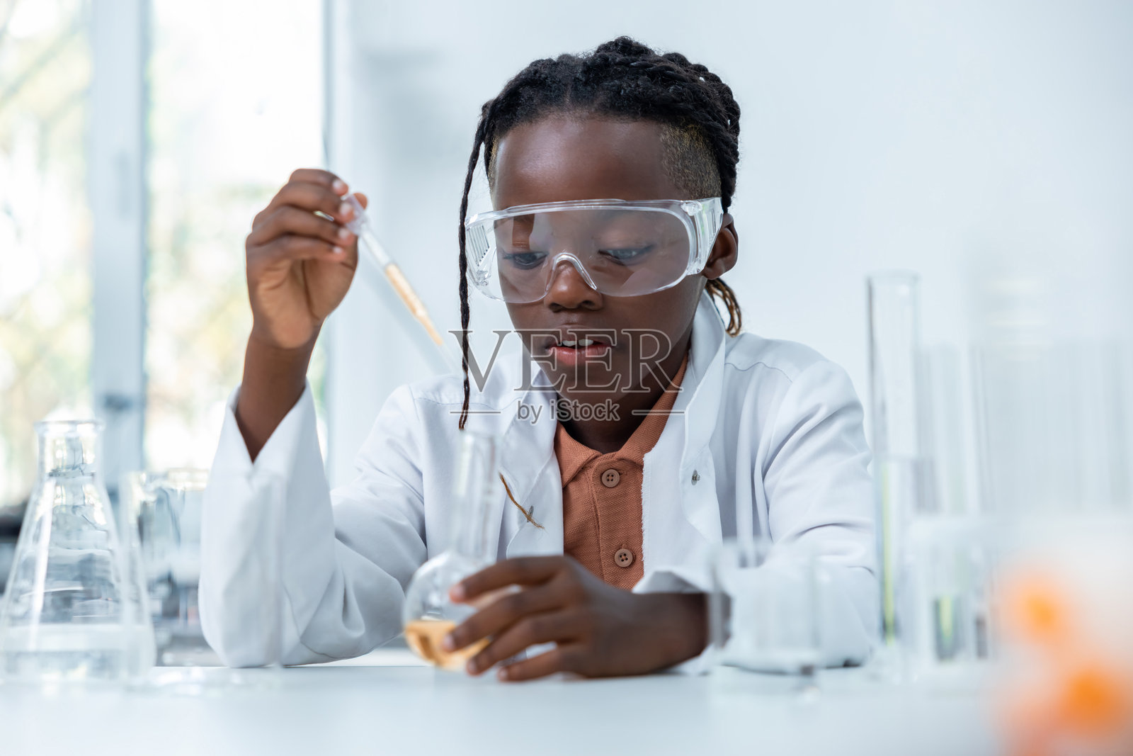 微笑的女性研究员在实验室中用培养皿和烧瓶分析化学液体照片摄影图片