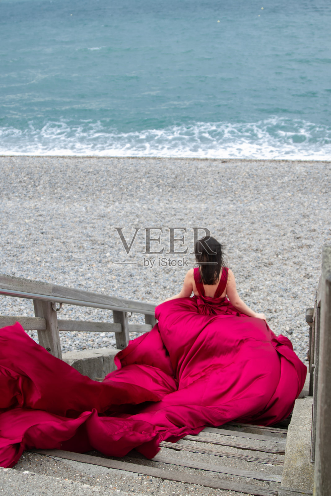 穿着红色裙子的女孩在诺曼底的海岸边照片摄影图片