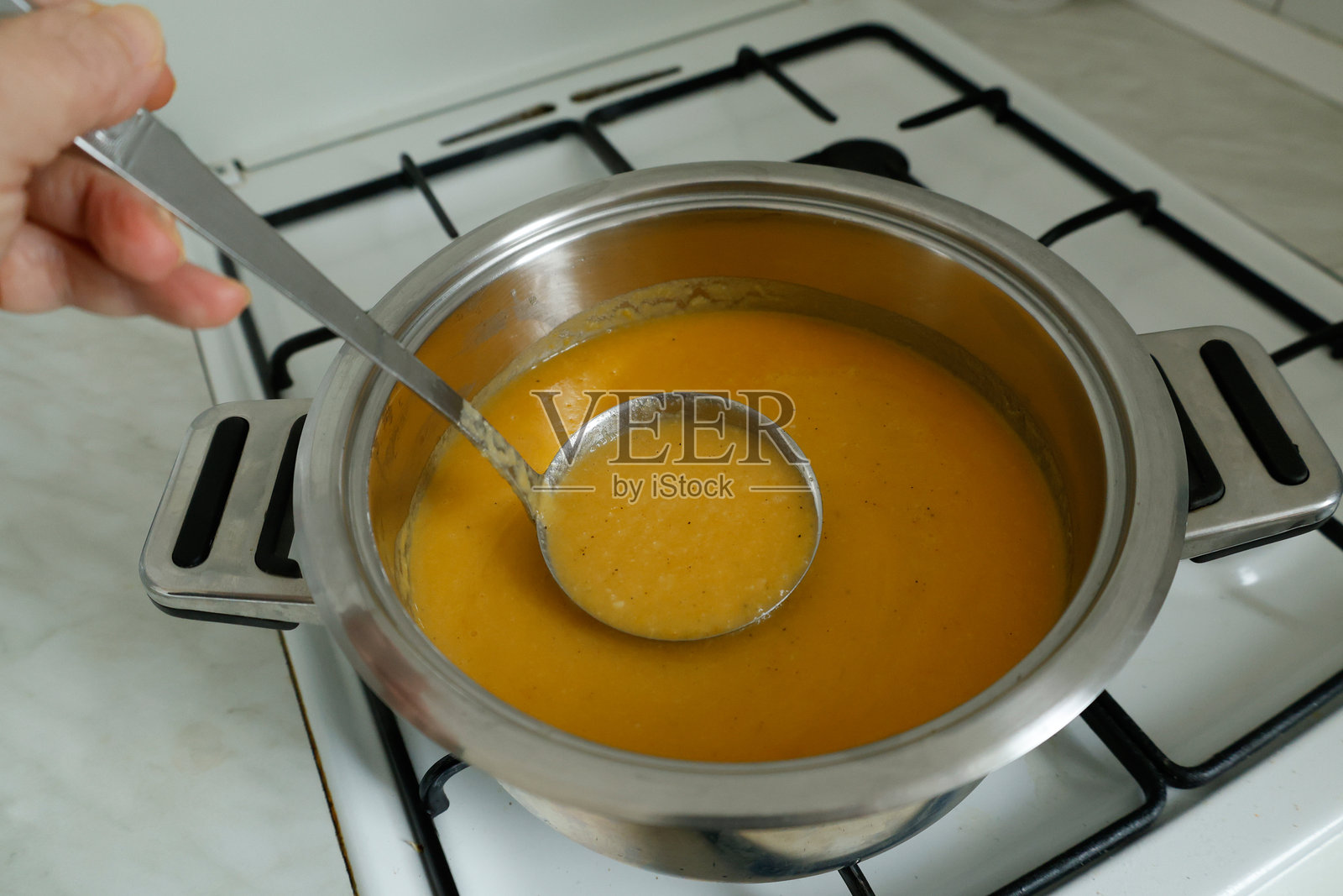 自制蔬菜汤的汤勺放在炉灶上照片摄影图片