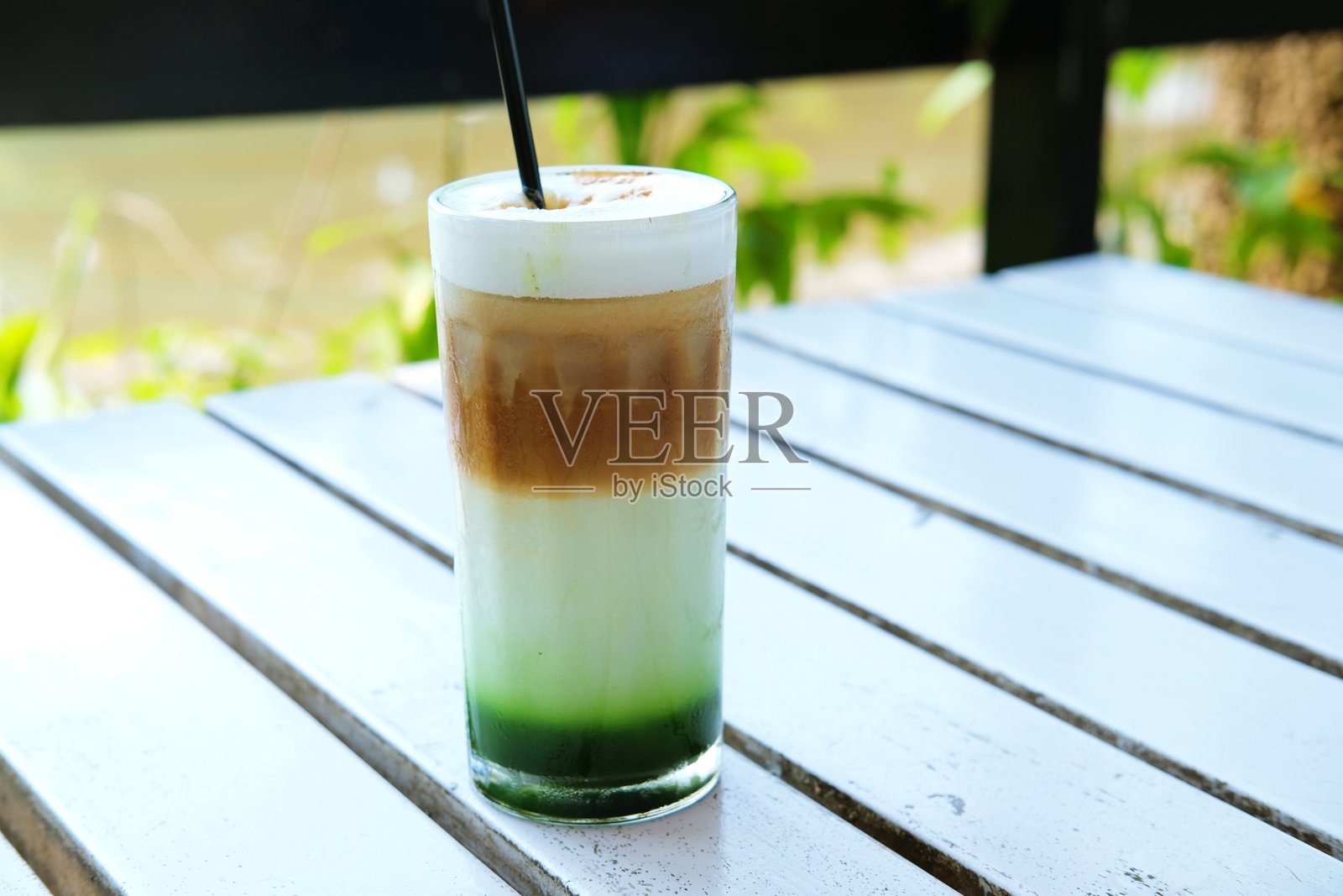 一杯清爽的绿茶、牛奶和咖啡分层饮料，装在高玻璃杯中照片摄影图片