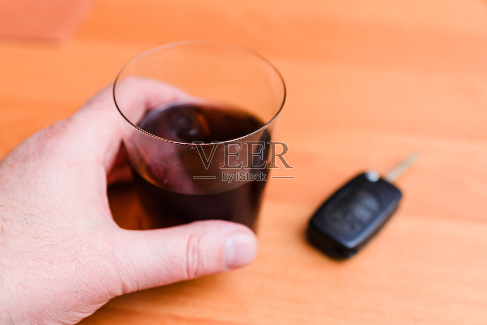 家中的桌子上放着汽车钥匙、酒杯、男人的手和啤酒罐。照片摄影图片