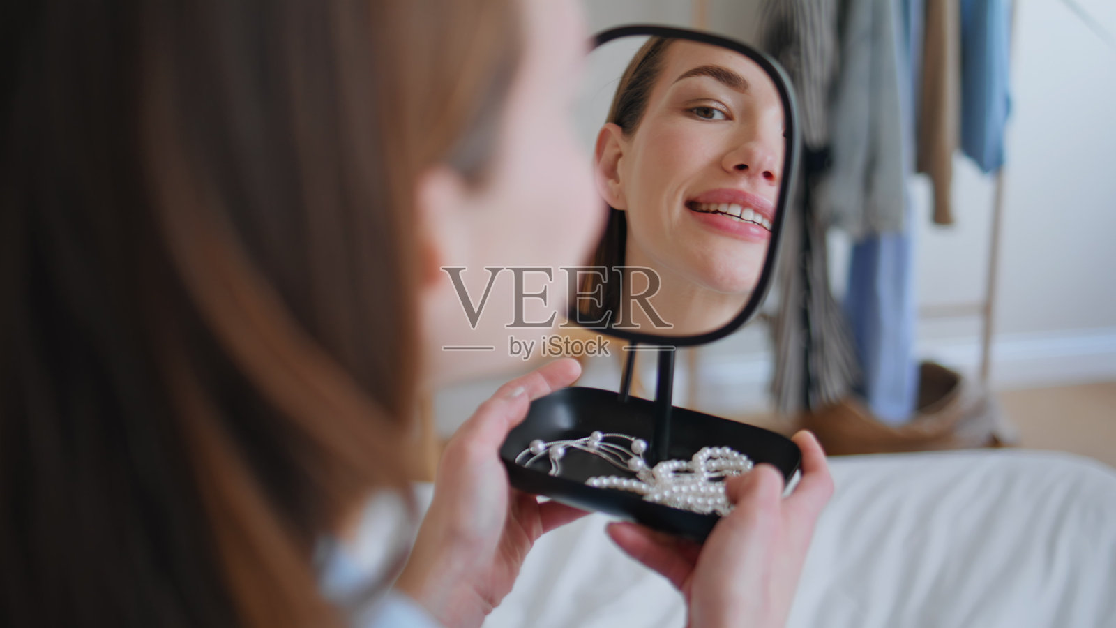 早晨的女士欣赏镜中倒影，手持手镜，近距离展示珠宝照片摄影图片