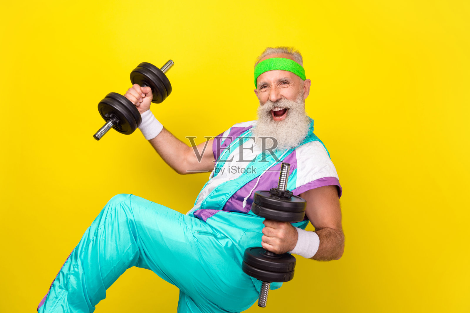 兴奋的帅气男人在黄色背景下举起哑铃的侧面肖像。照片摄影图片