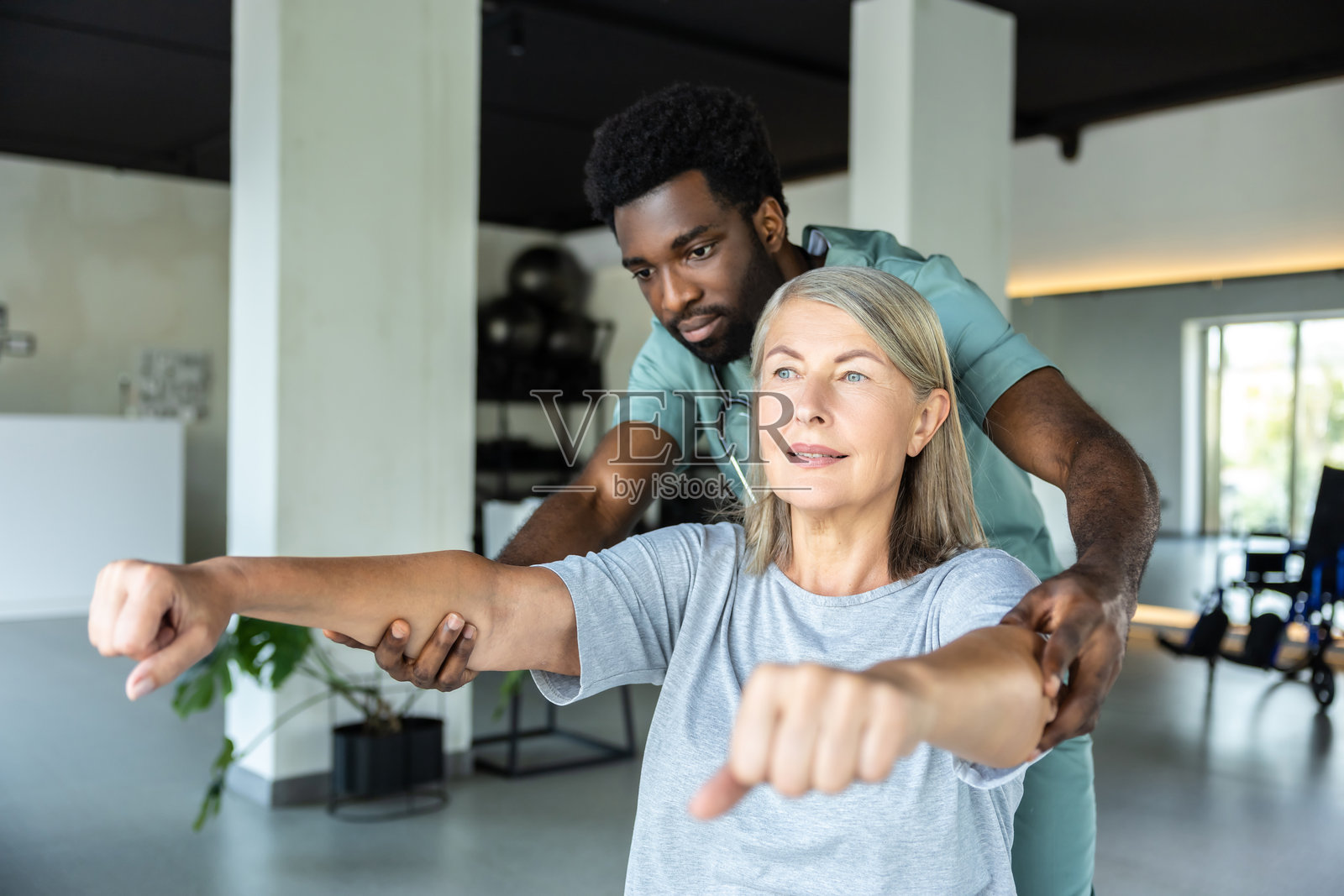 物理治疗师在诊所帮助成年患者进行手臂疼痛缓解的物理治疗和康复。照片摄影图片