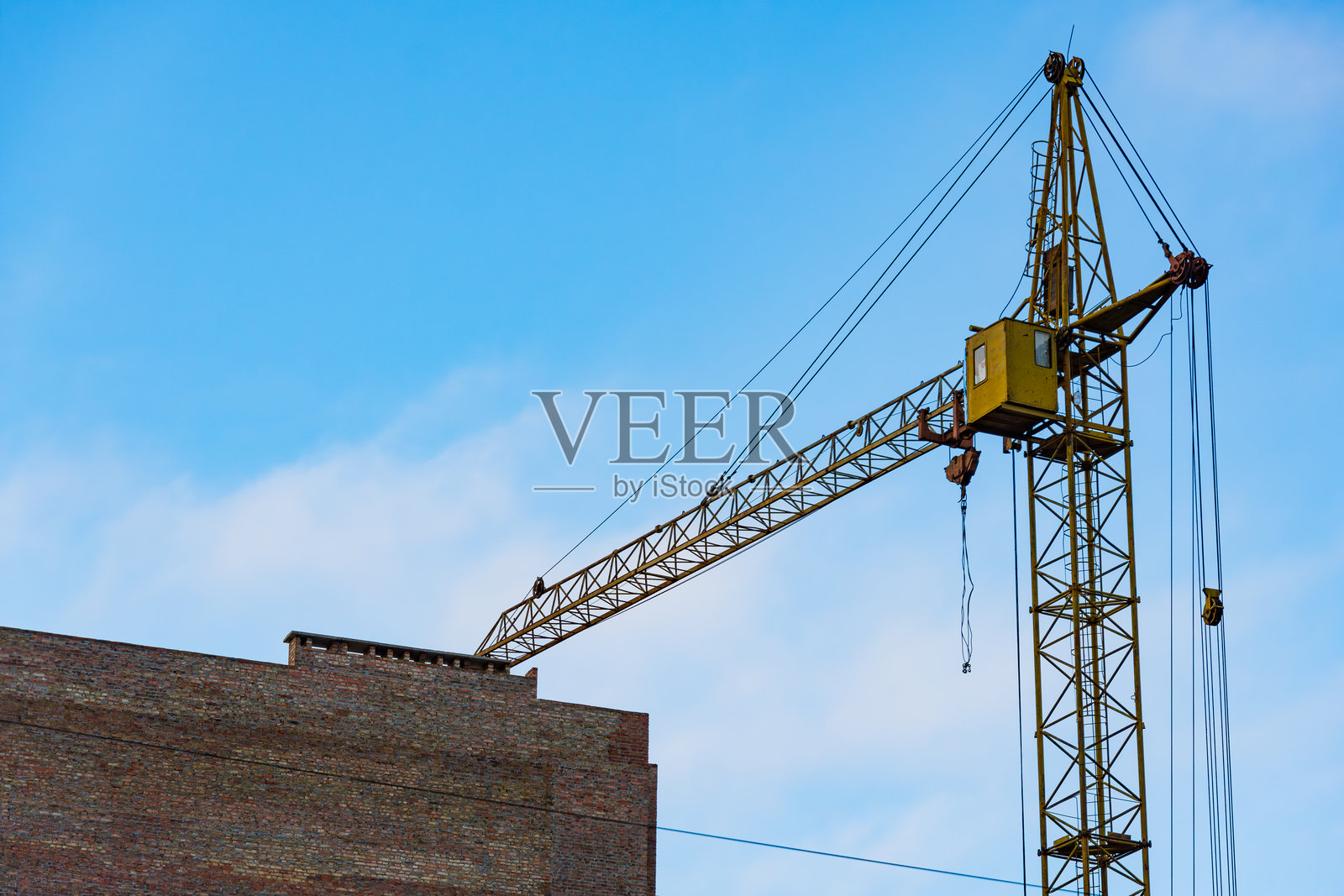 一台高大的起重机位于建筑工地，伸向一座建筑结构，下面的工人们正在努力工作。照片摄影图片