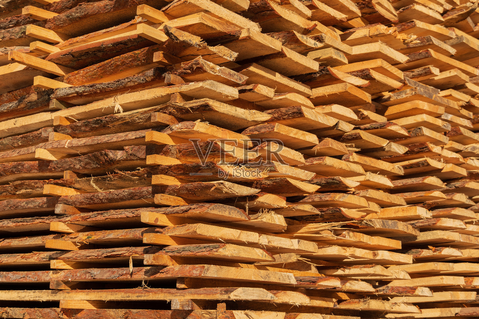 阳光透过锯木厂的木材堆，照亮整齐排列的新鲜木板。木材的温暖色调突显了纹理，展示了优质的木材。照片摄影图片