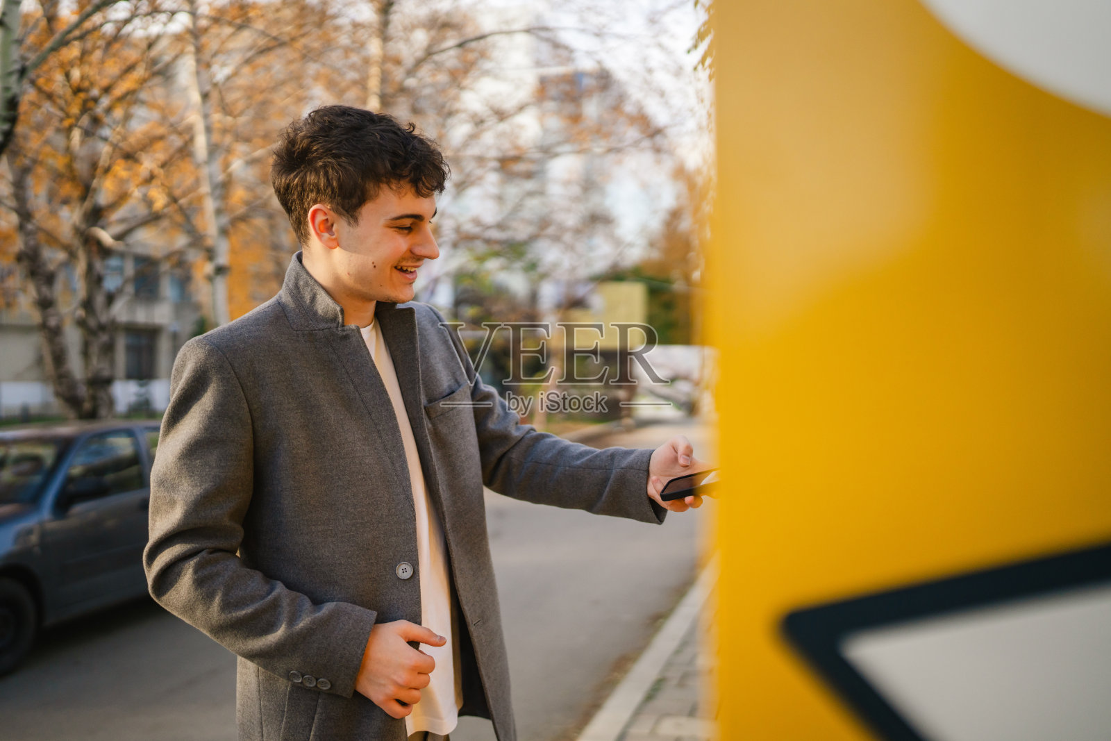 年轻男子在户外的包裹机上用智能手机扫描二维码照片摄影图片