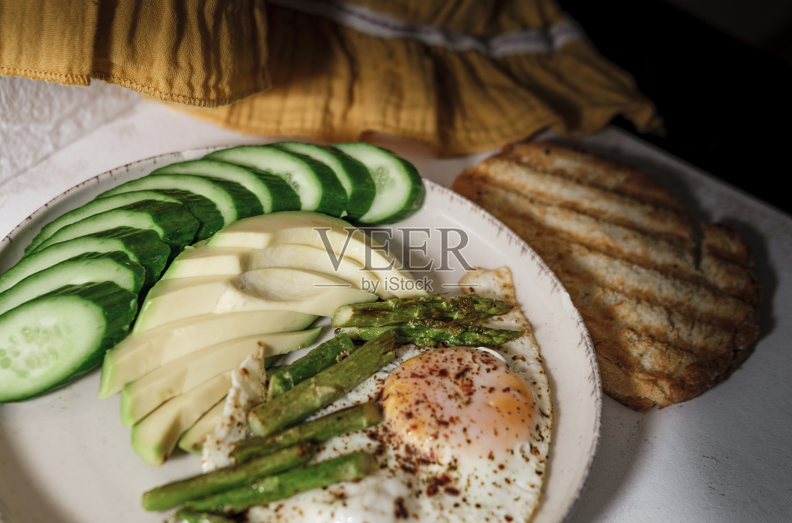 早晨早餐的空白空间，鳄梨、黄瓜、煎蛋、芦笋在浅色背景上，绿色蔬菜，一片面包照片摄影图片