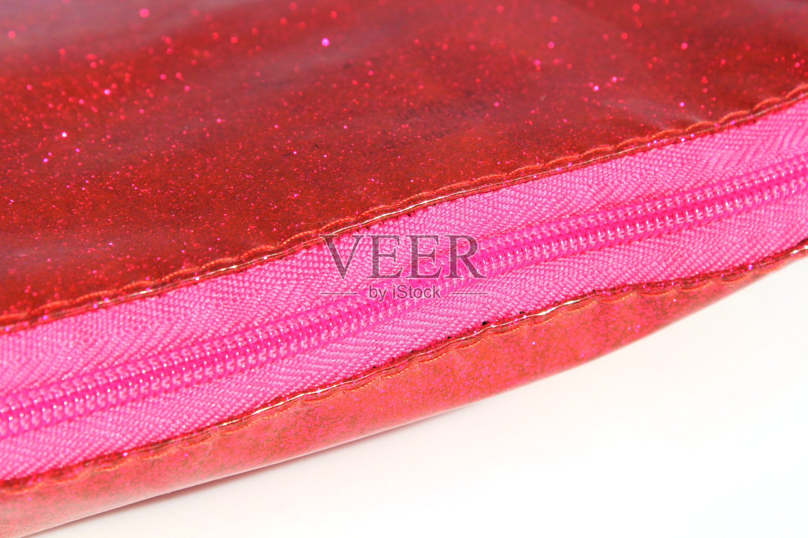 红色闪光包上的粉色拉链特写，背景为白色。照片摄影图片