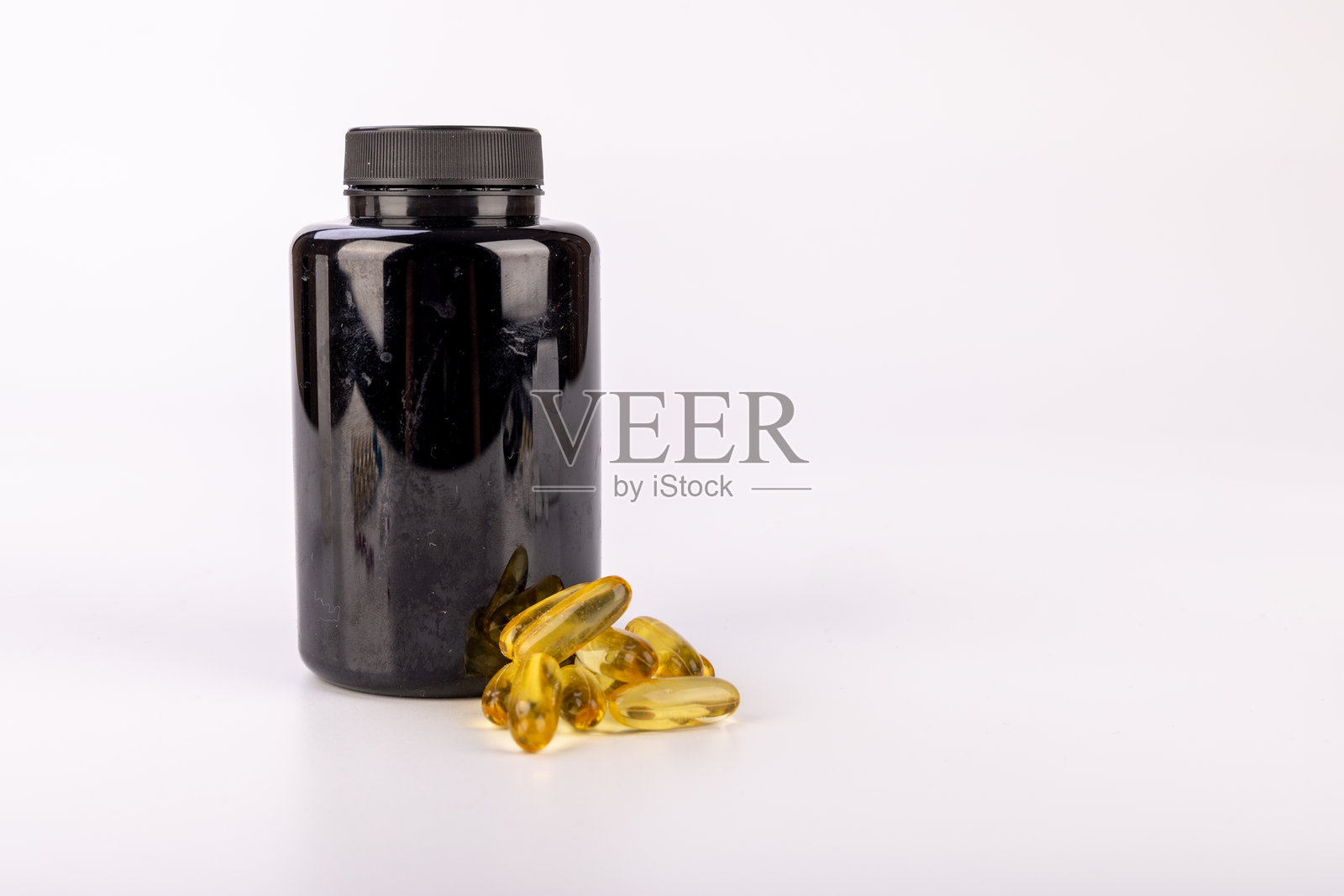 黑色药瓶与黄色药丸放在白色平面上照片摄影图片