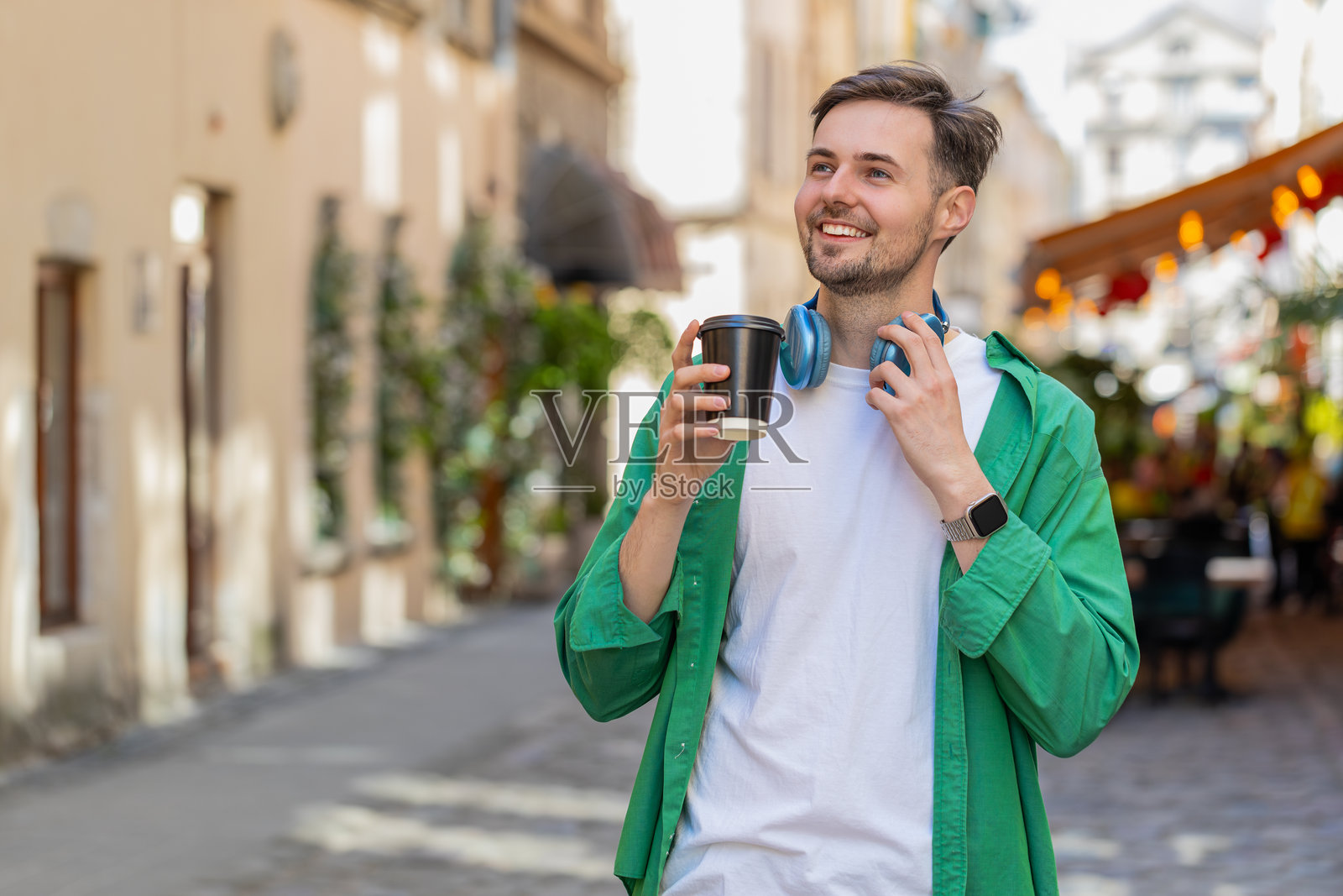 快乐的男人在城市街道上享受早晨咖啡，微笑放松，休息片刻。照片摄影图片