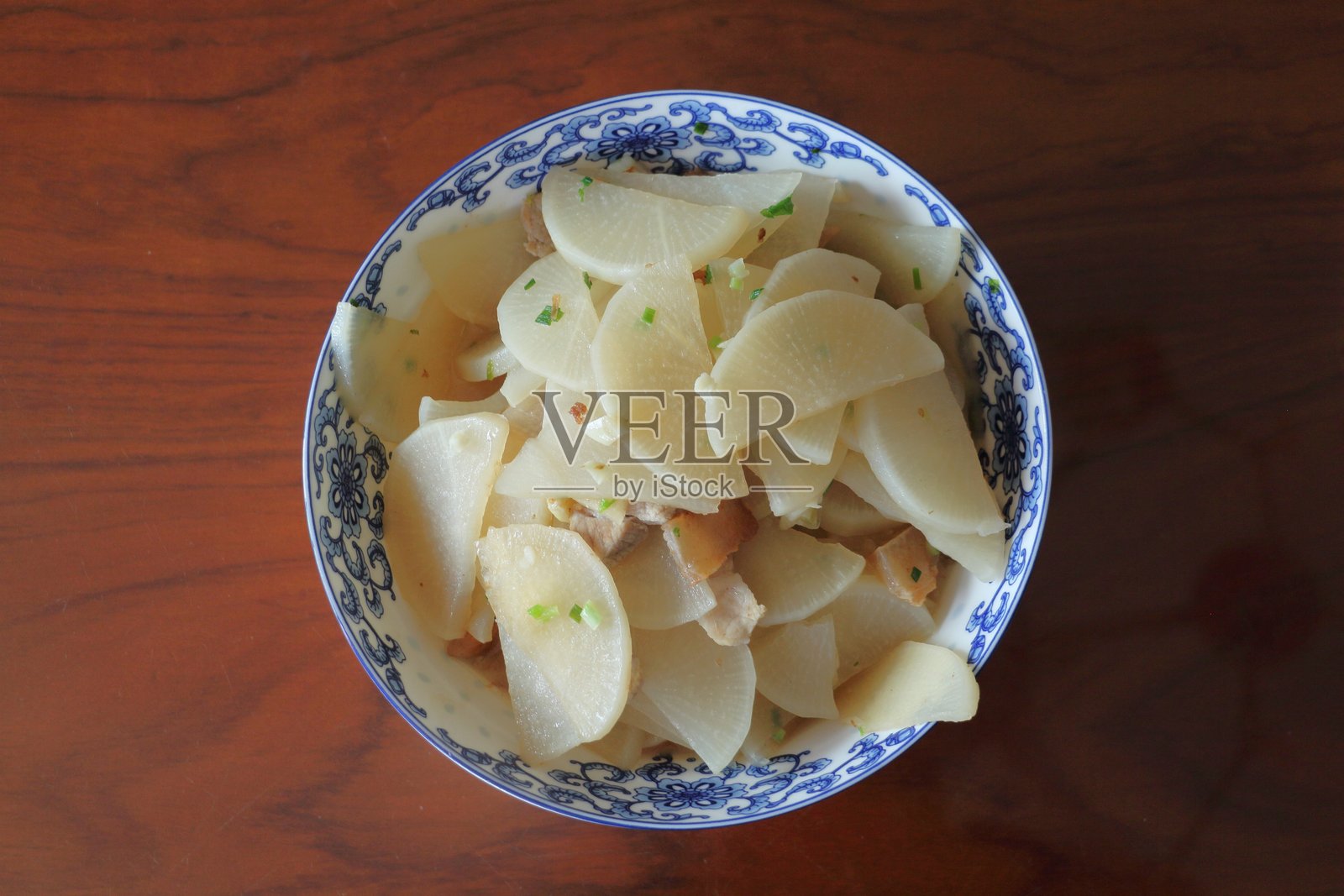 新鲜制作的白萝卜沙拉盛在传统的蓝白相间碗中，放在木桌上。照片摄影图片