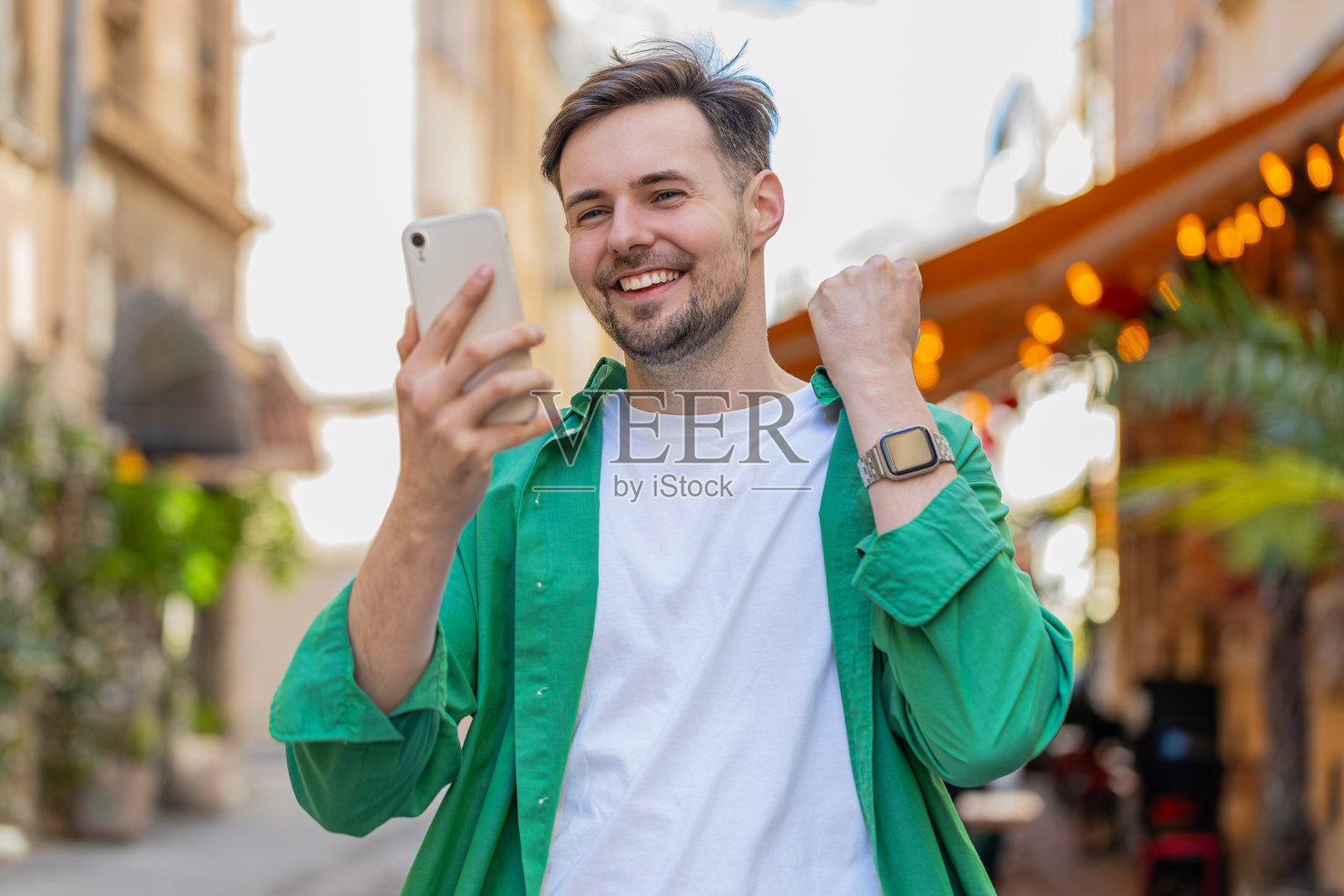 快乐的男人使用手机庆祝中奖的好消息，彩票赌场大奖胜利照片摄影图片