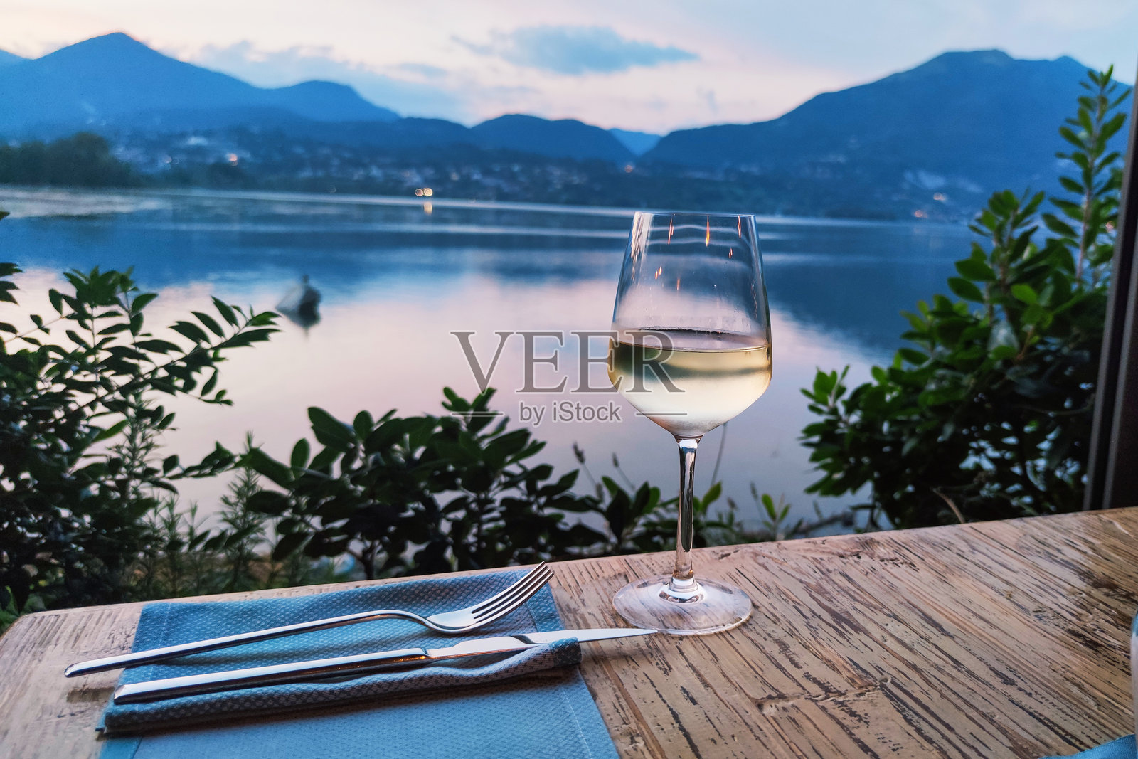 意大利普西亚诺湖的晚餐，伴随一杯白葡萄酒，日落时分照片摄影图片