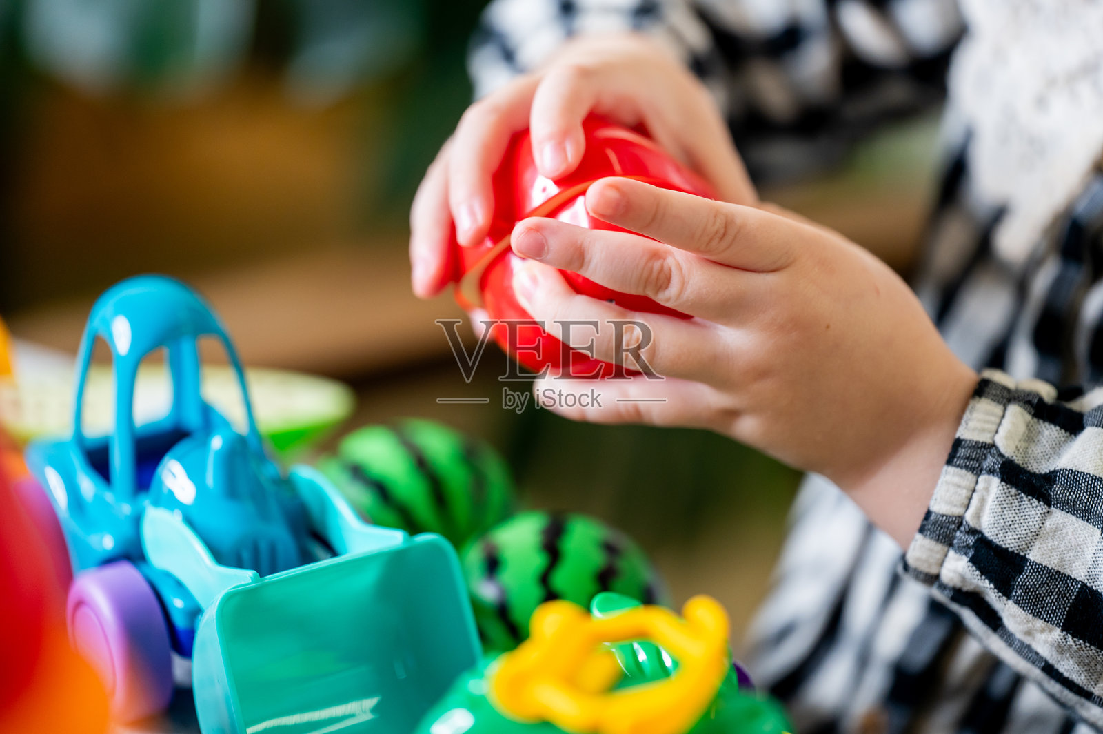 一个孩子在玩五颜六色的玩具蔬菜，增强了精细运动技能和创造力。这些鲜艳的塑料水果和蔬菜整齐地摆放在桌子上，非常适合进行富有想象力的游戏。照片摄影图片