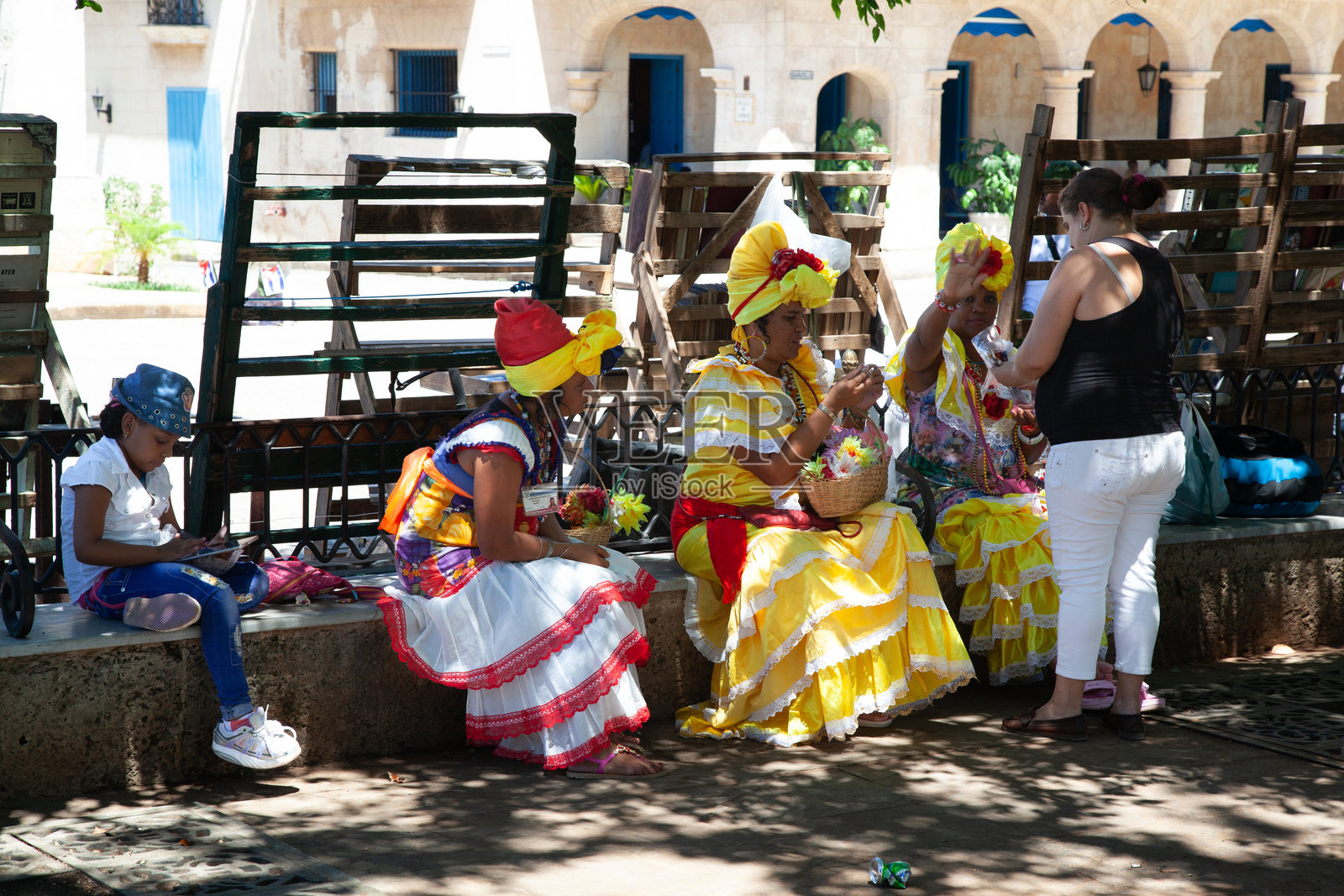 穿着黄色和红色的典型女性在古哈瓦那的武器广场上照片摄影图片