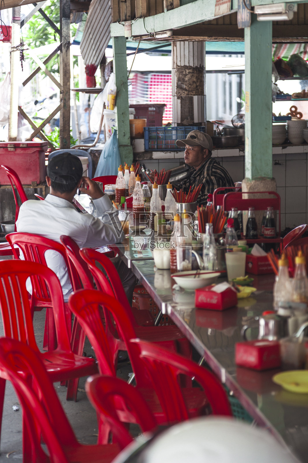 在当地的金边餐馆享受用餐体验，红色椅子充满活力，热闹非凡。照片摄影图片